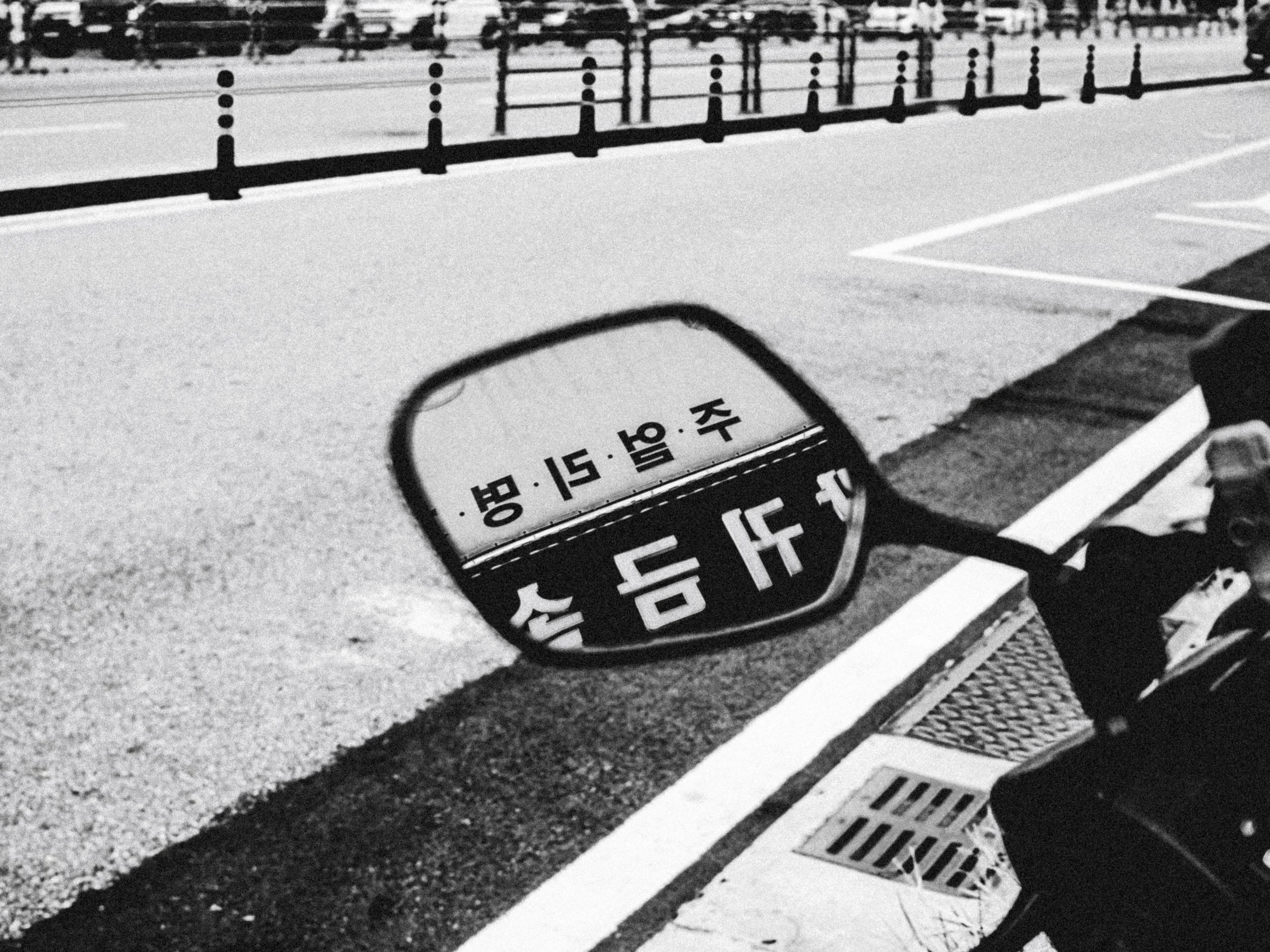 Close-up of a manhole cover with Japanese characters on a concrete surface next to a pedestrian crosswalk.