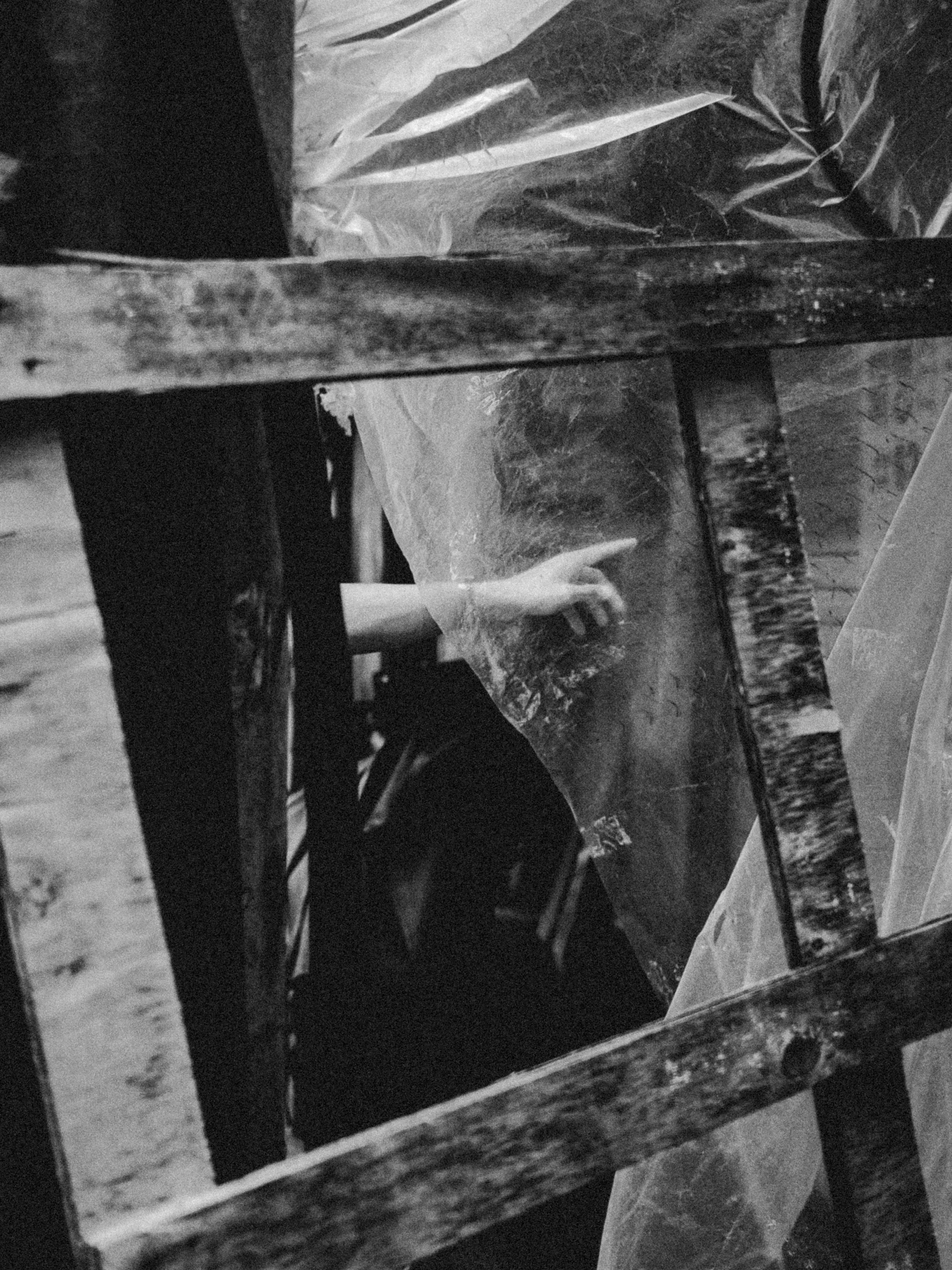 A black and white photo showing a close-up of a display case with jewelry or small objects inside, a hand reaches in to pick up or examine an item.