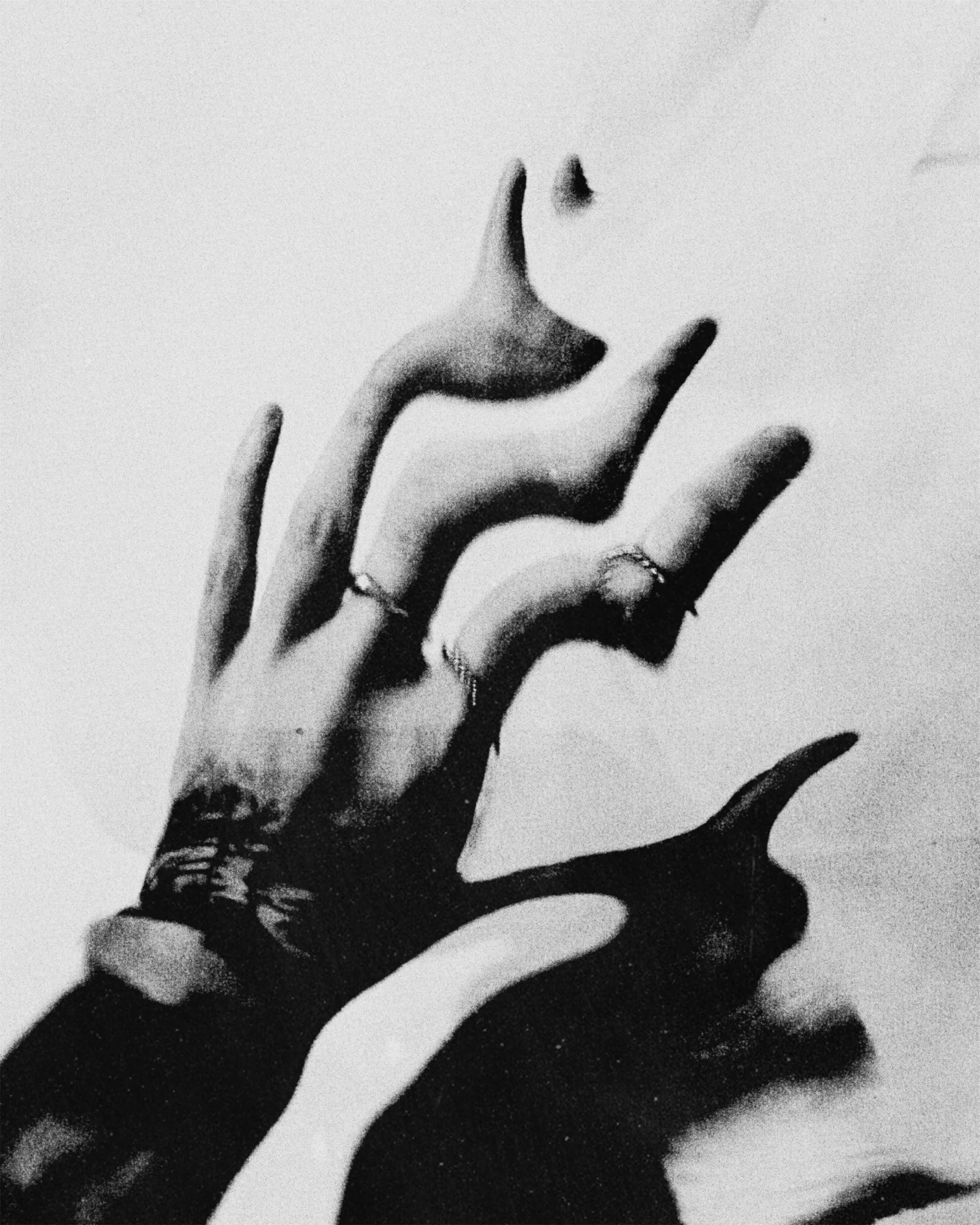 A black and white artistic photo of a hand near the face, with fingers partially covering the lips, creating a moody and expressive atmosphere.