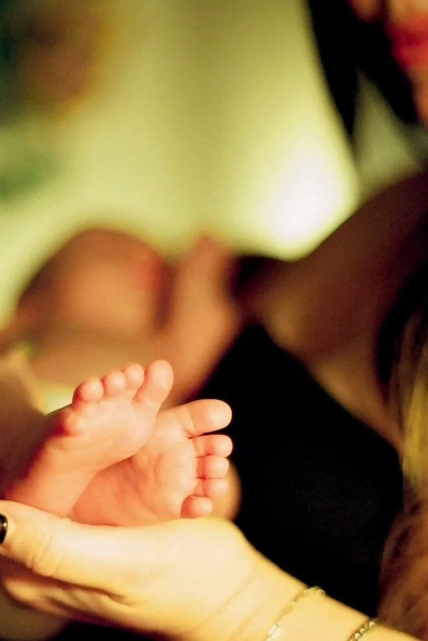 Mother, mom, holding newborn baby feet, comfortable at home.