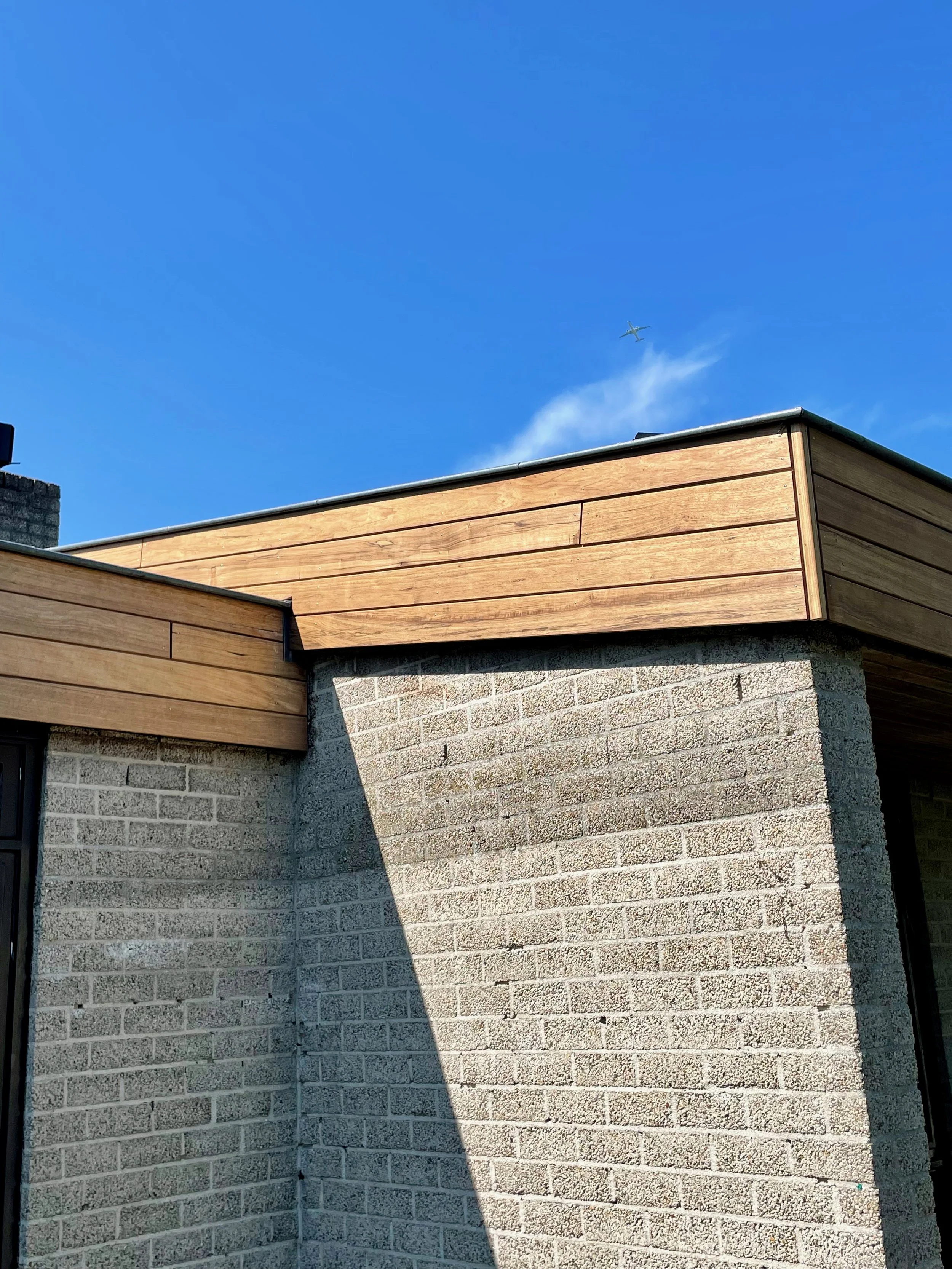 De afbeelding toont een gebouw met een gevel van houten planken, volledige vervanging door Mats van soolingen Bouw regio Amsterdam. Jouw buitenwerk kan er weer jaren tegenaan.