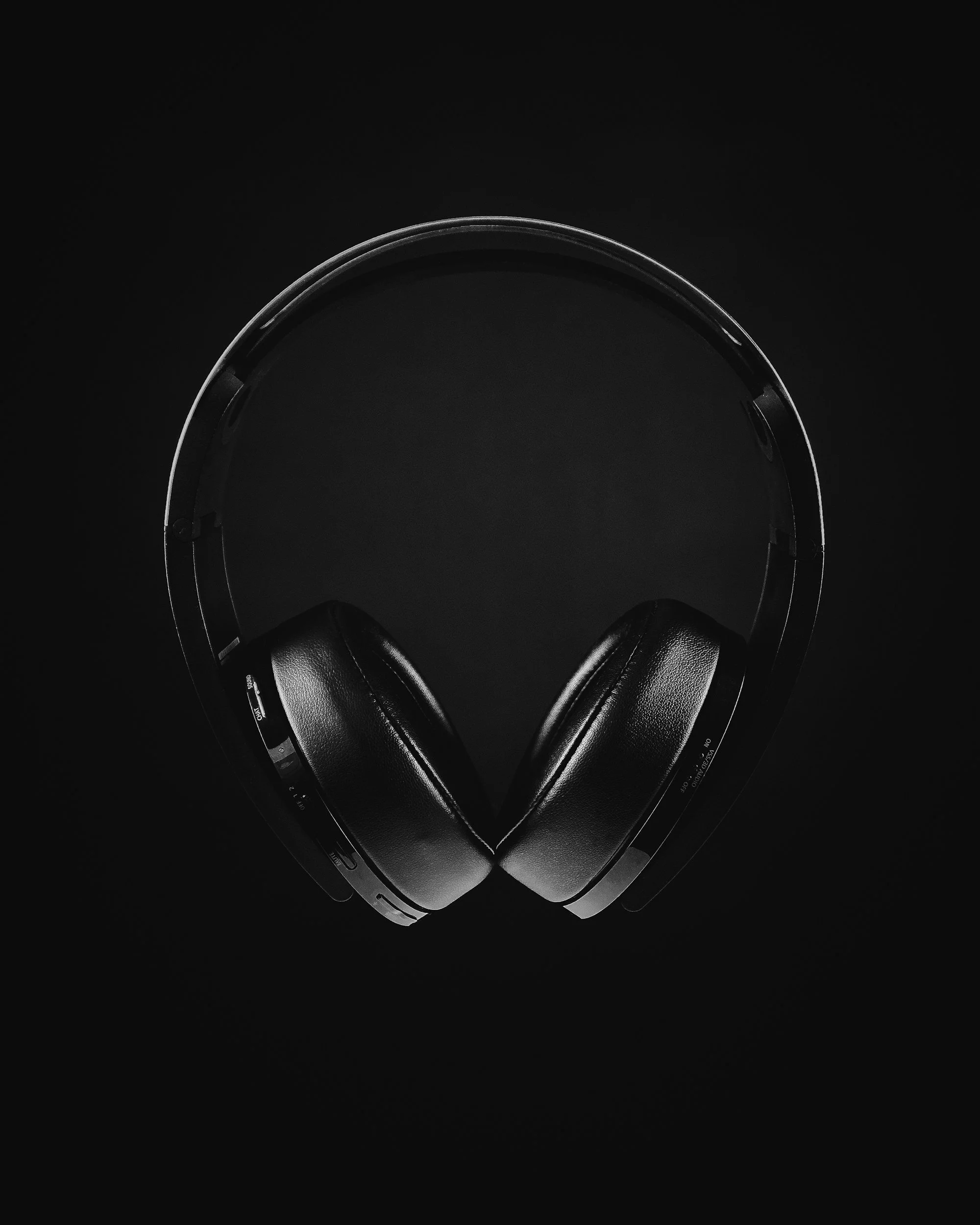 Black wireless over-ear headphones on a dark background.