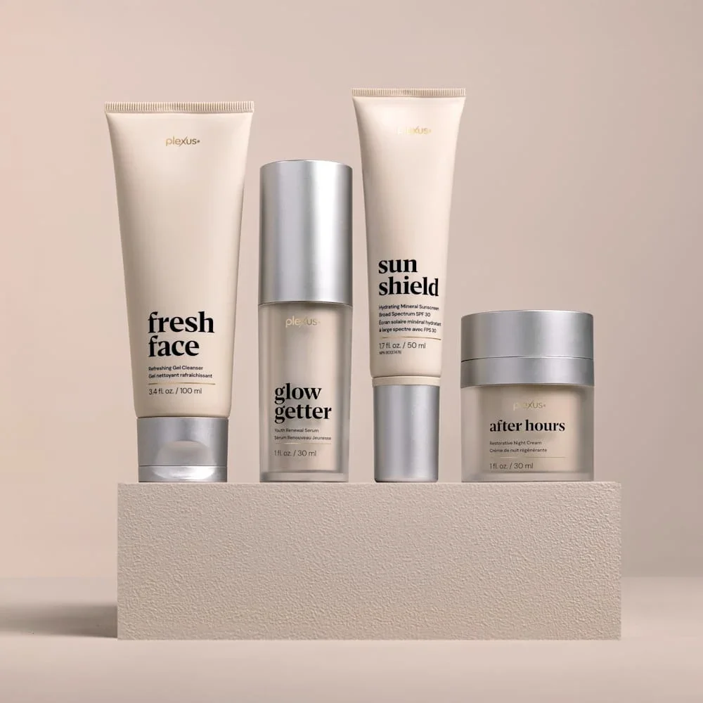 A collection of skincare products including Fresh Face gel cleanser, Glow Getter serum, Sun Shield mineral sunscreen, and After Hours night cream displayed on a beige platform