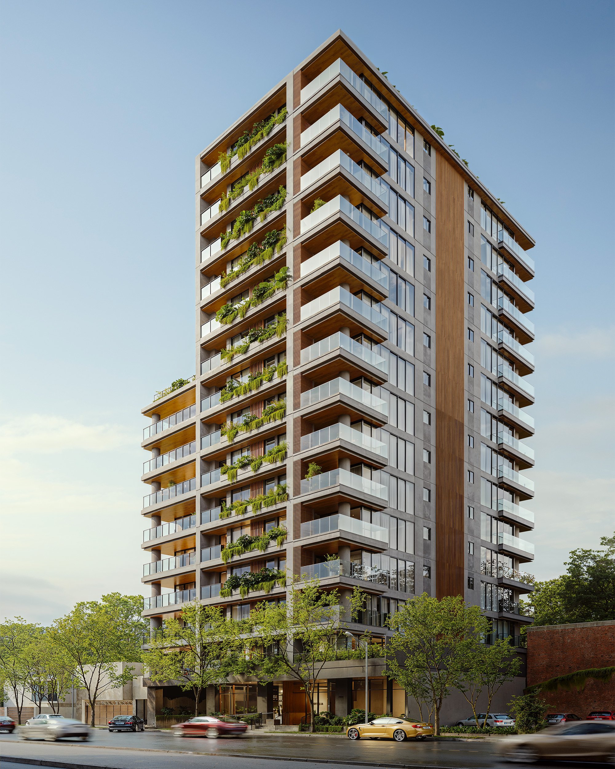 Edificio moderno de varios pisos con balcones y plantas verdes, árboles en la calle y autos en movimiento bajo un cielo despejado.