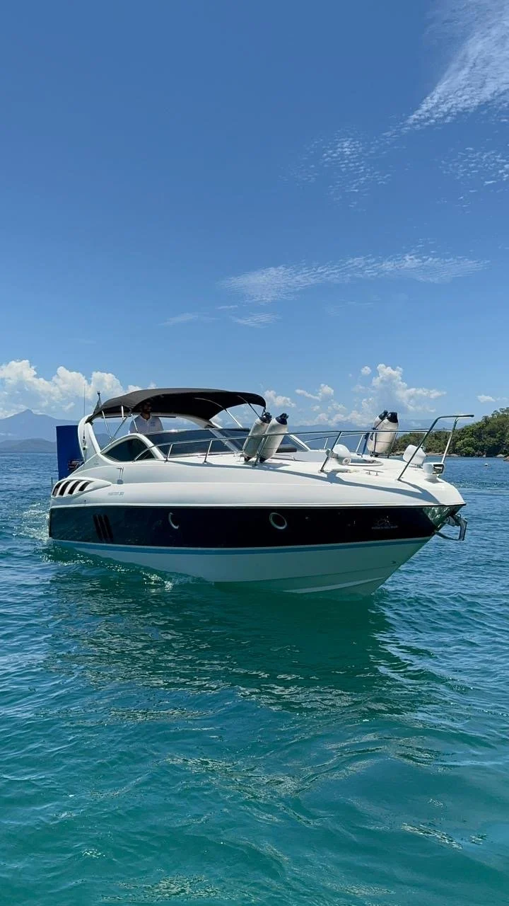 A white motor yacht cruising on turquoise water under a blue sky with scattered clouds.