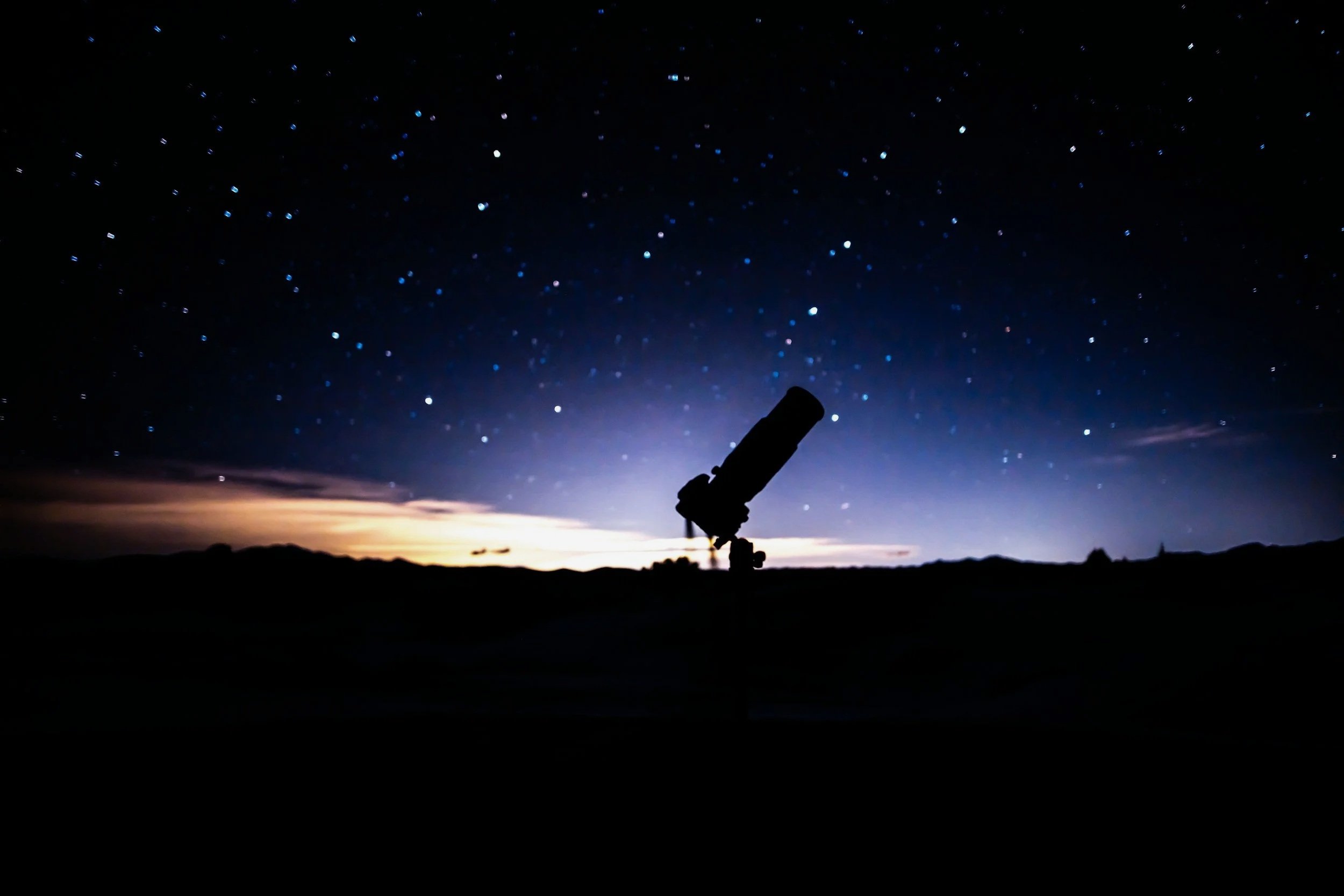 Telescope in front of a starry night sky.