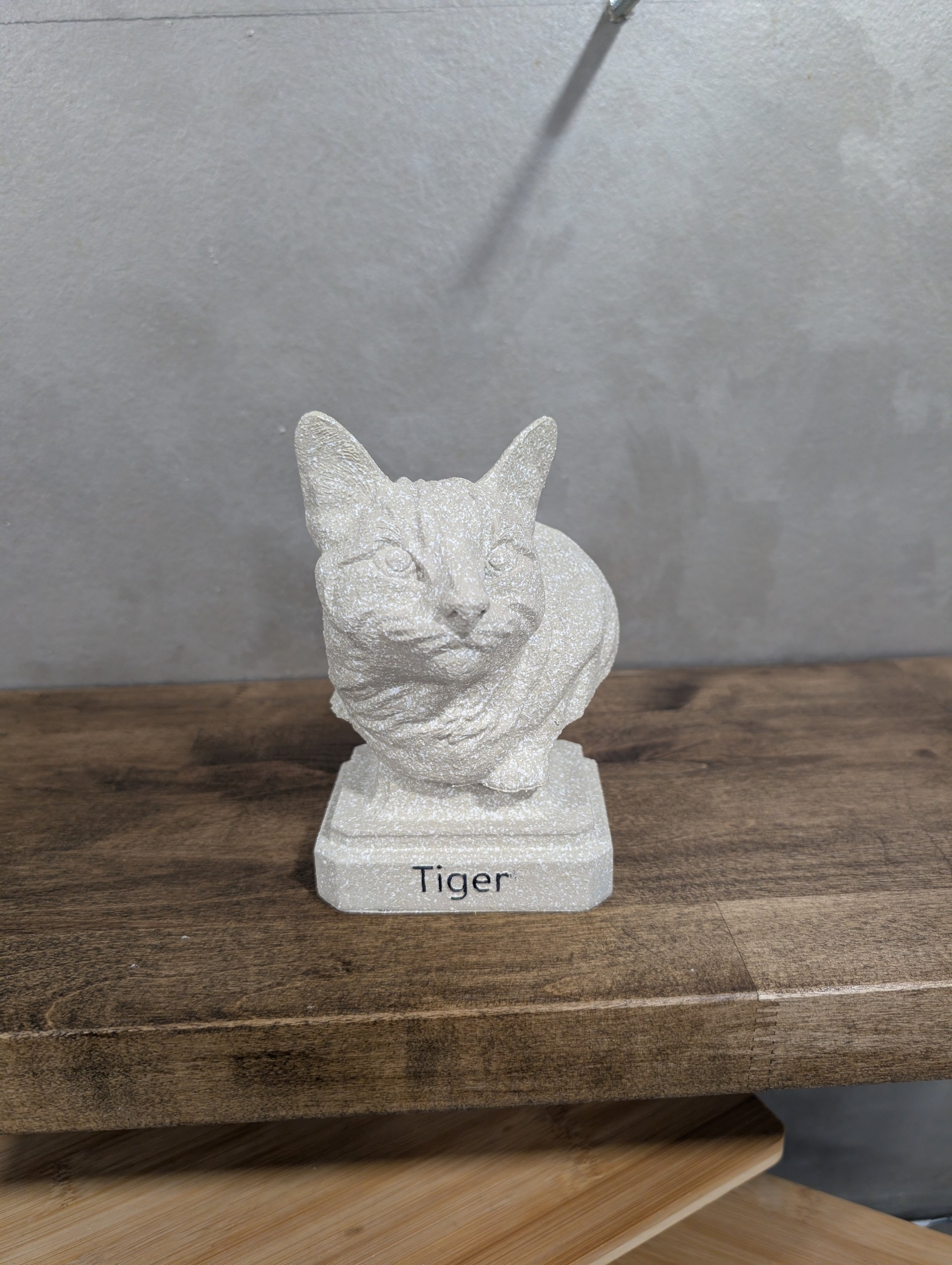 White sculpture of a tiger on a wooden surface with a label that says 'Tiger'.