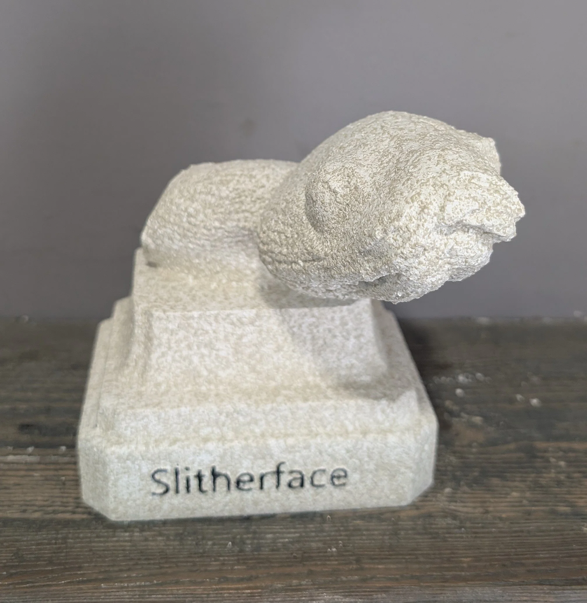 Sculpture of a slithering snake made of textured white material with the word 'Slitherface' engraved on the base.