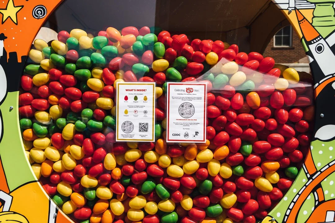 Colorful eggs in red, green, yellow, and orange inside a vending machine with cartoonish design and informational signs.