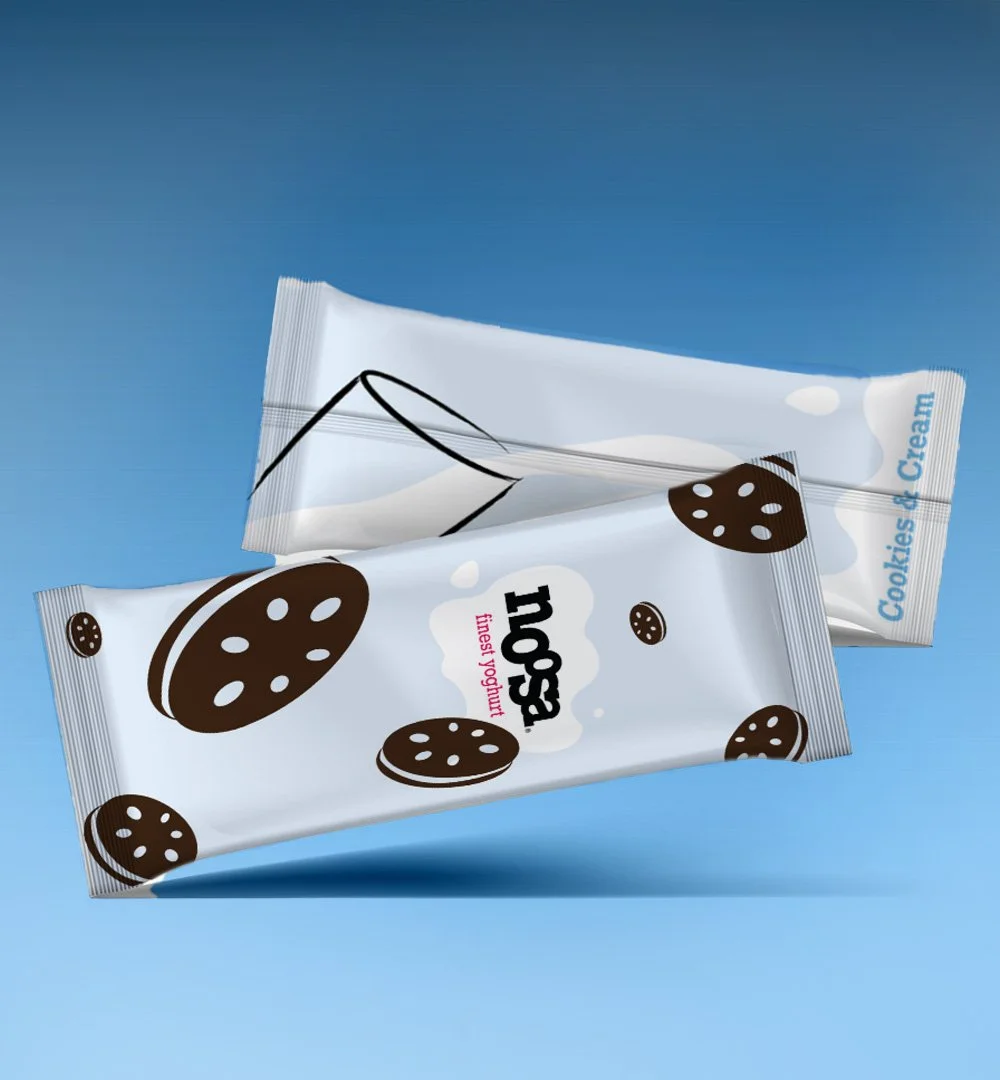 Two snack-sized packages of Trope cookies and cream flavored yogurt on a gradient blue background.