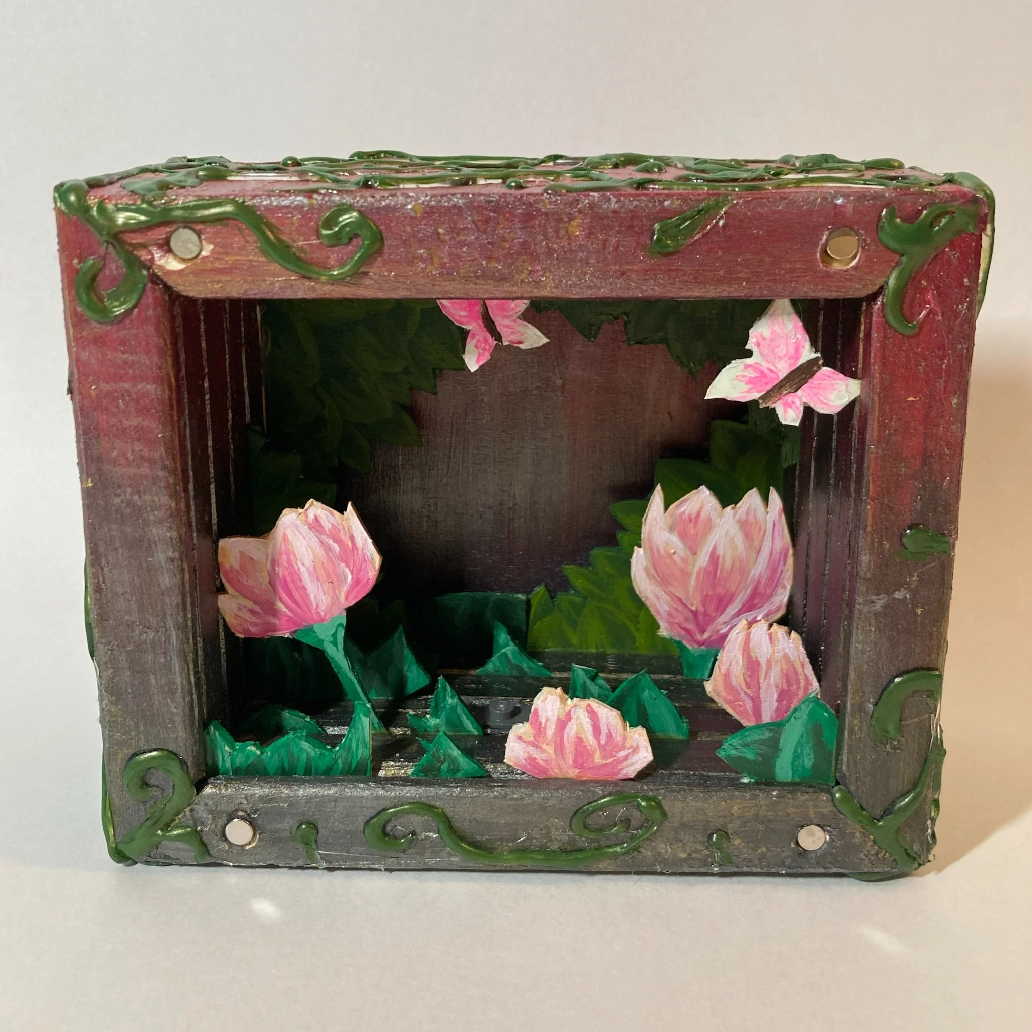 Decorative wooden box with pink lotus flowers and green leaves inside.