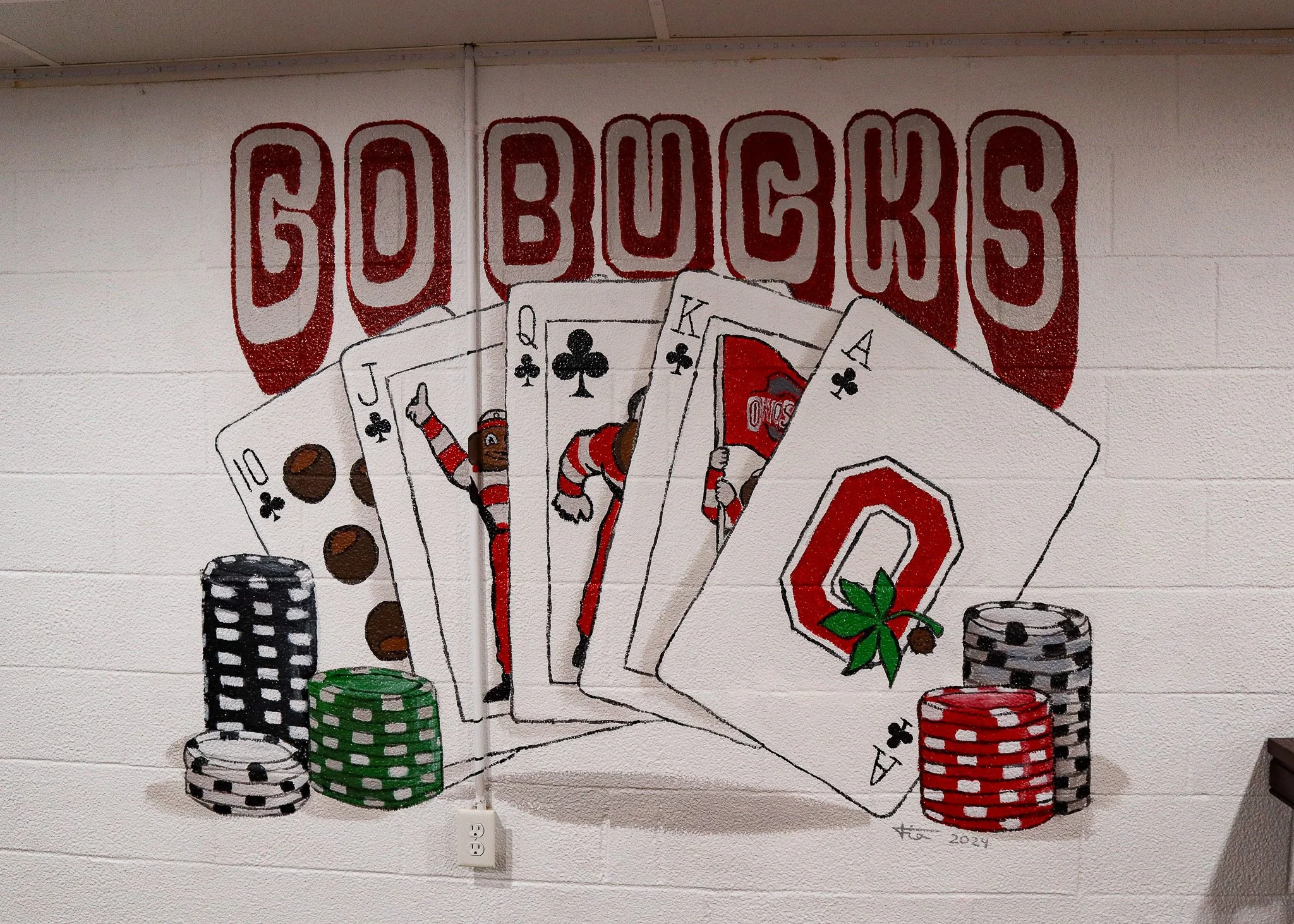 Wall art featuring playing cards, poker chips, and the words 'Go Bucks' in red and white letters.