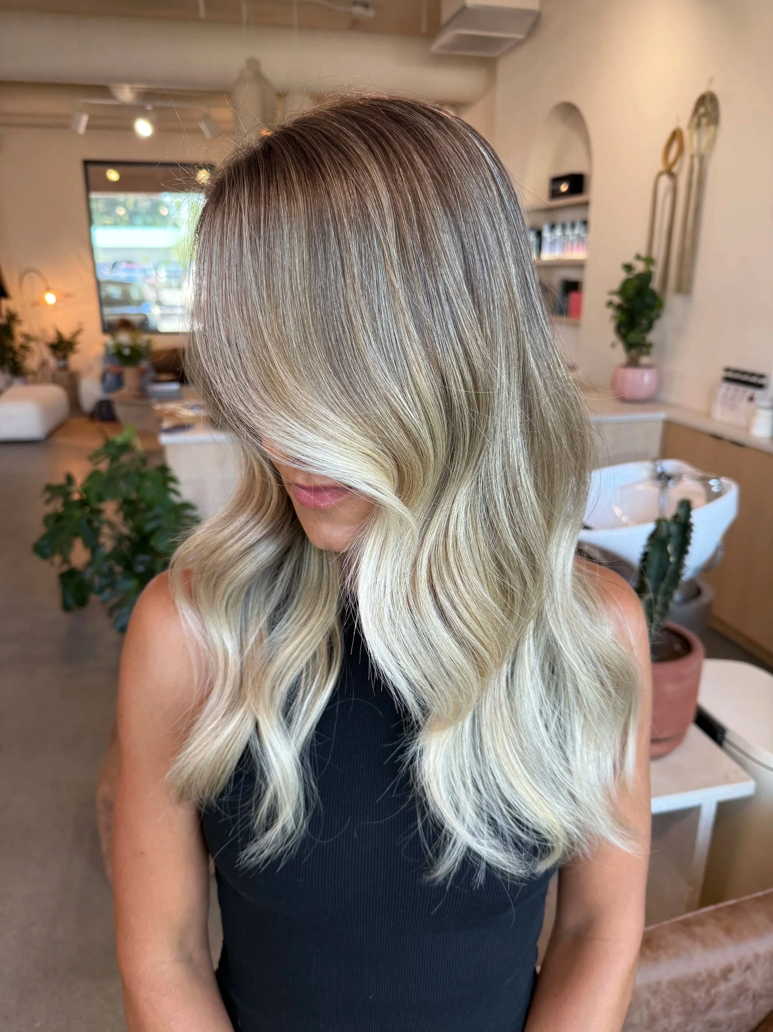 A woman with long, wavy blonde hair in a hair salon.