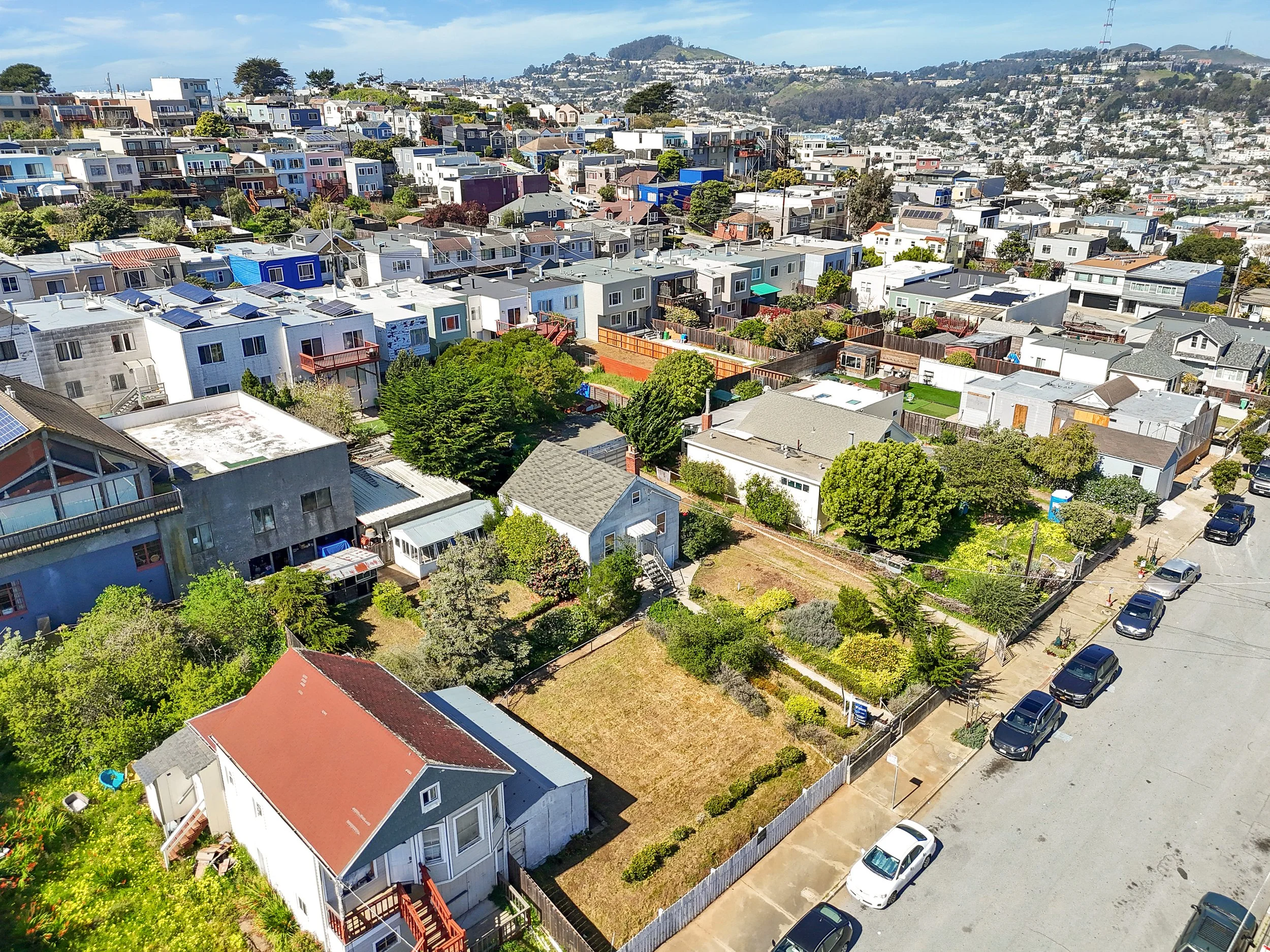 Aerial view of a neighborhood with houses, trees, and parked cars.