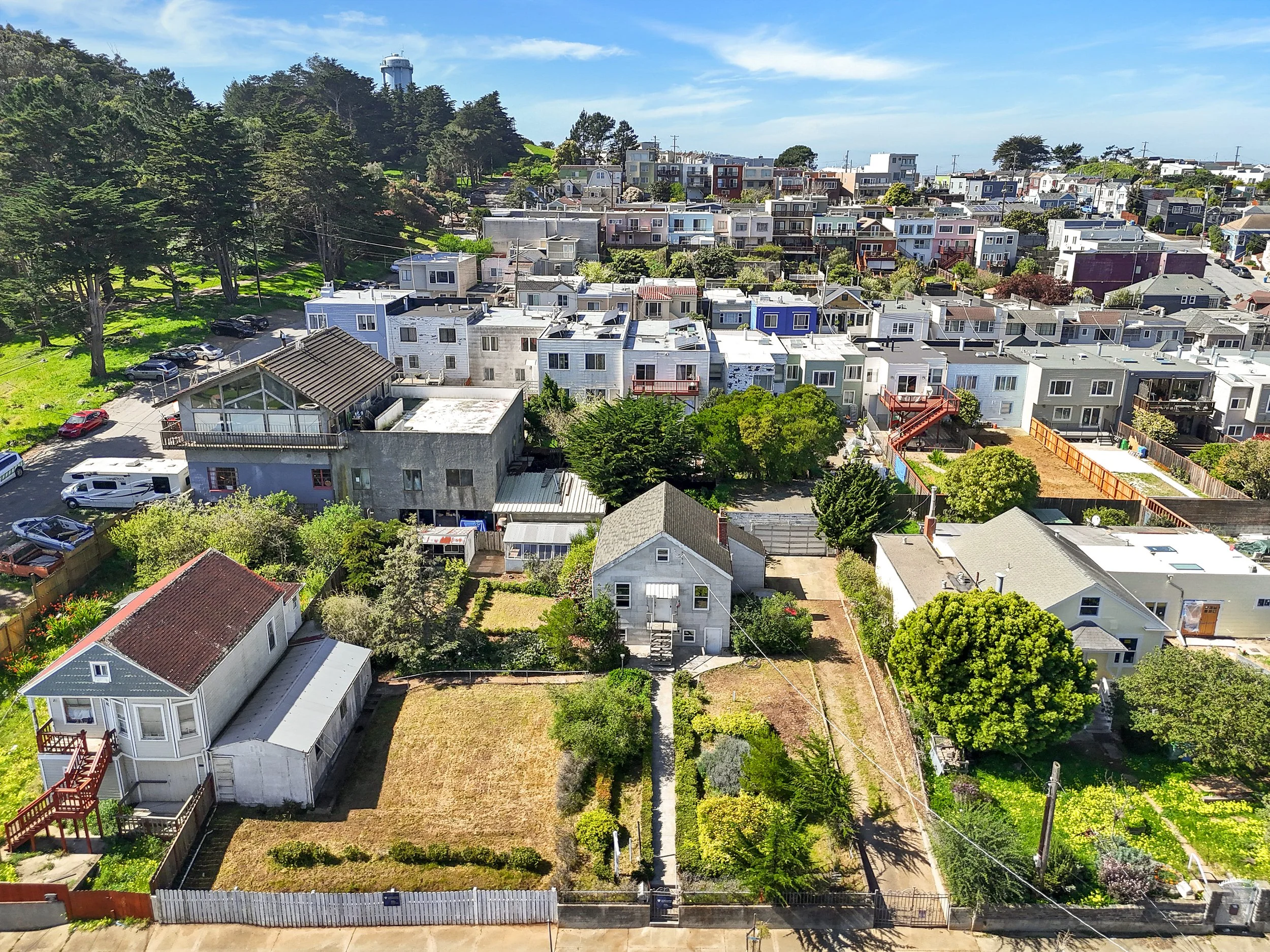 Aerial view of a residential neighborhood with houses, trees, and streets under a partly cloudy sky.