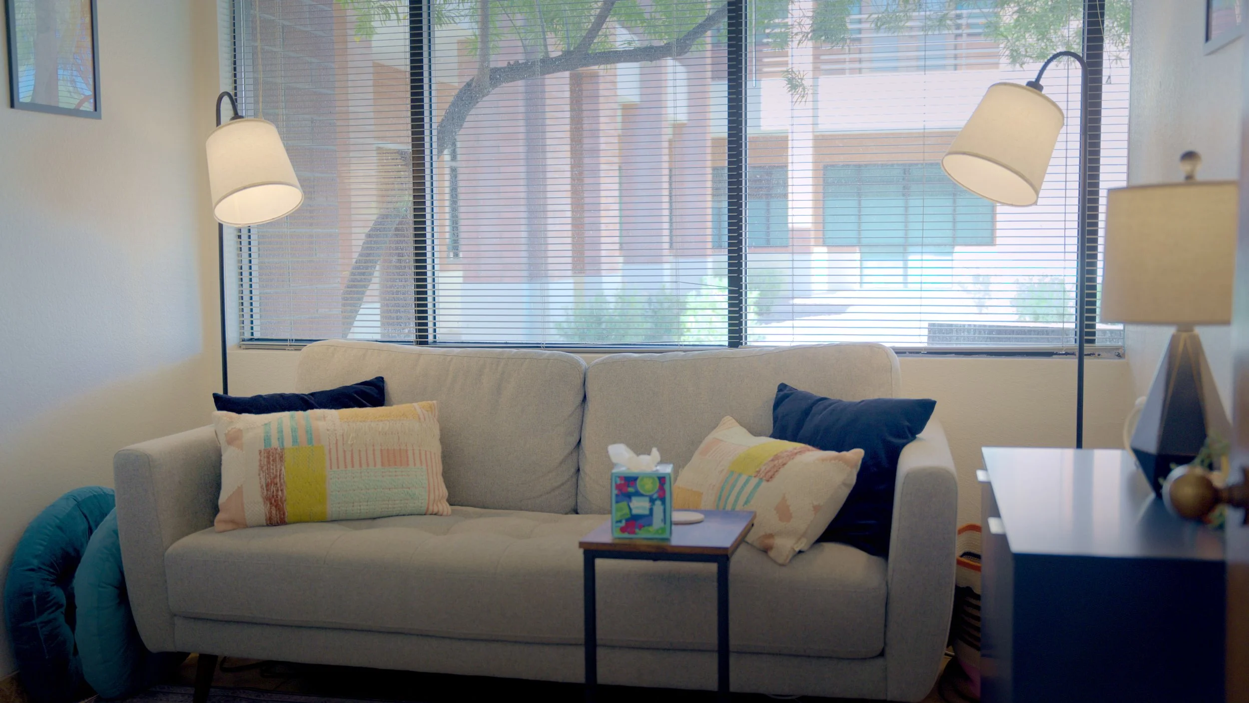 Bright counseling office with a couch, lamps, and large window