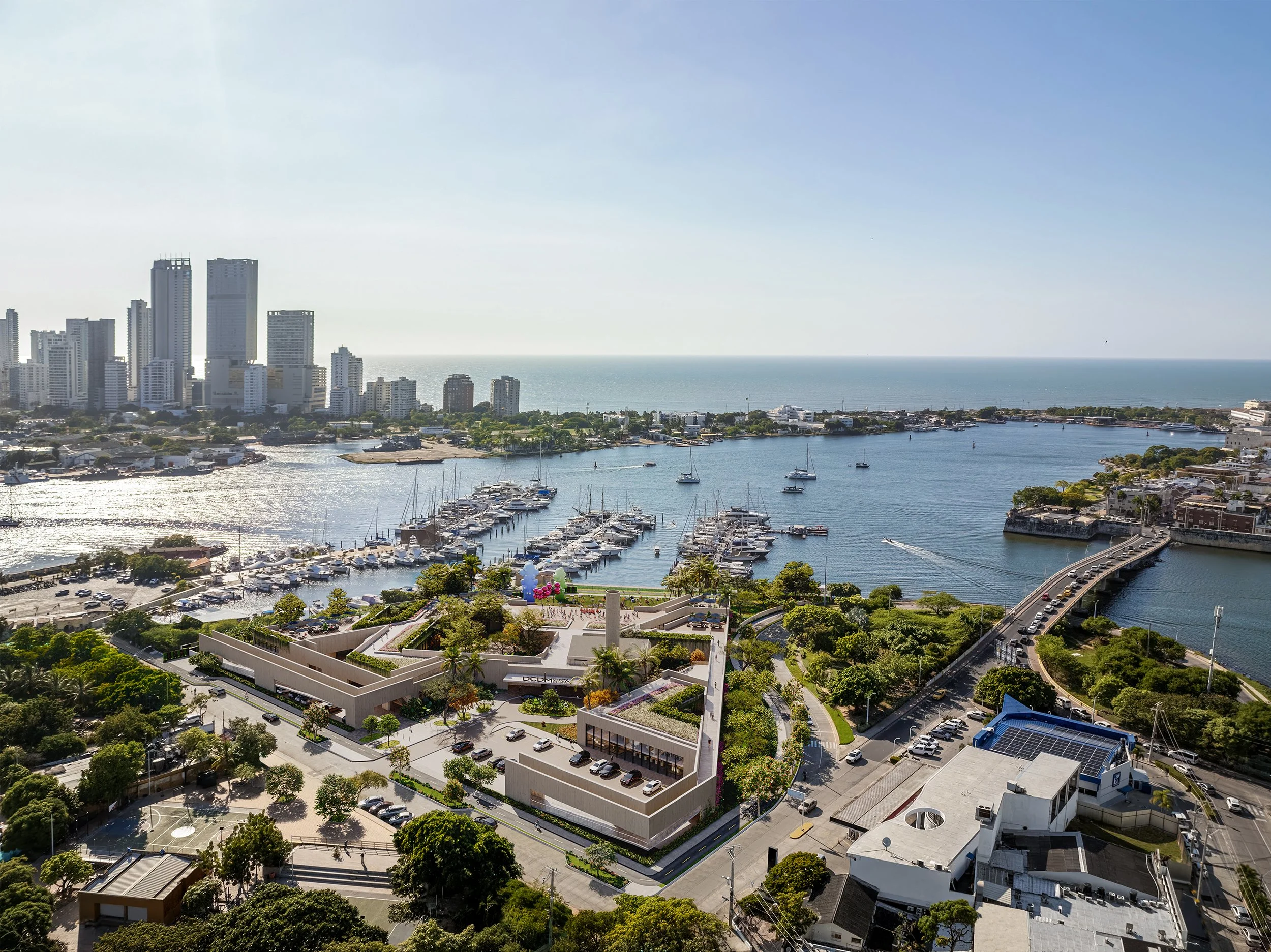 Aerial view of a coastal city with high-rise buildings, marina with boats, and green parks, by the ocean on a sunny day.