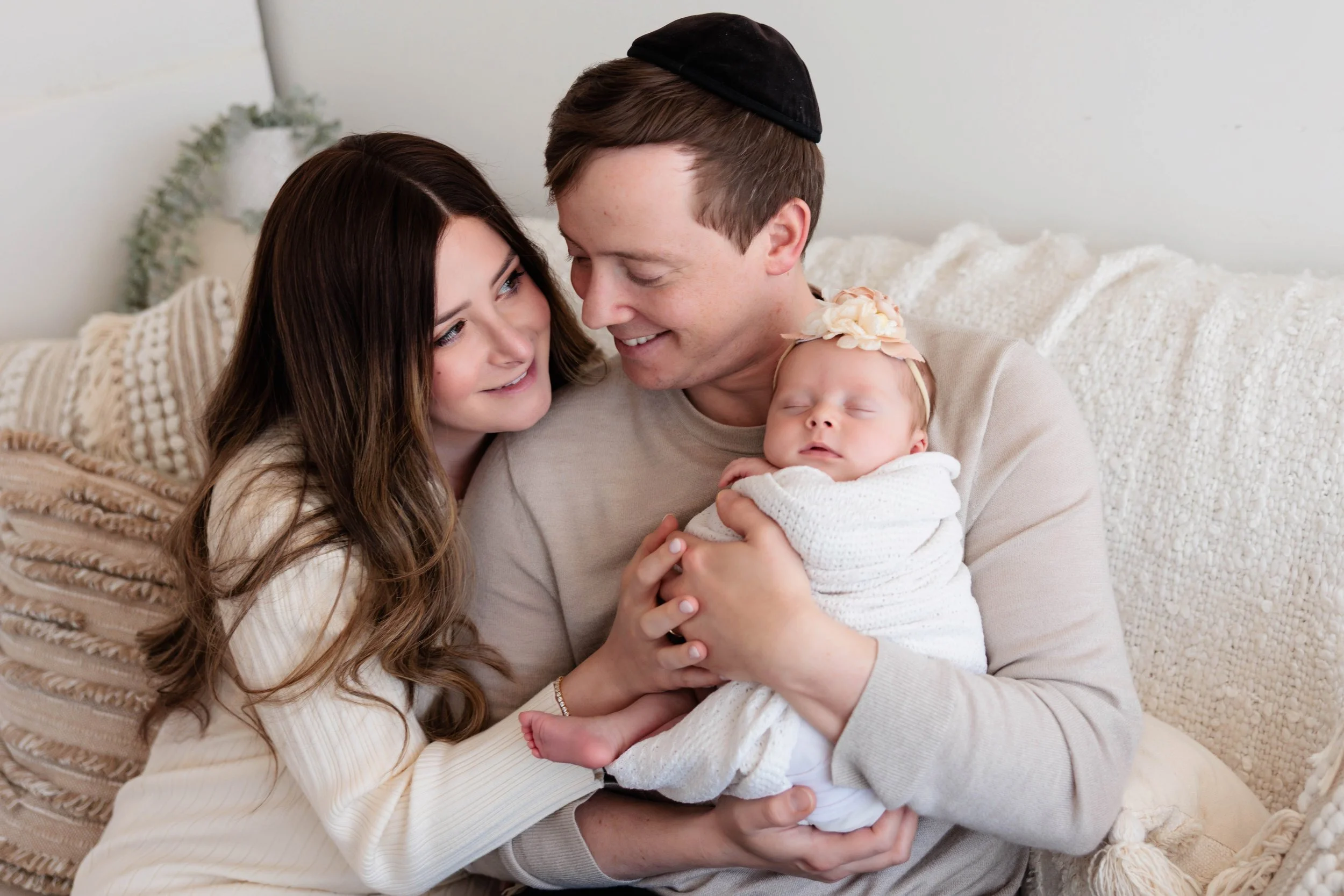 A family sitting in a BOHO style setting snuggling a newborn baby girl.  Family Newborn Photos.  Newborn Photography.  Family photos with a newborn. 