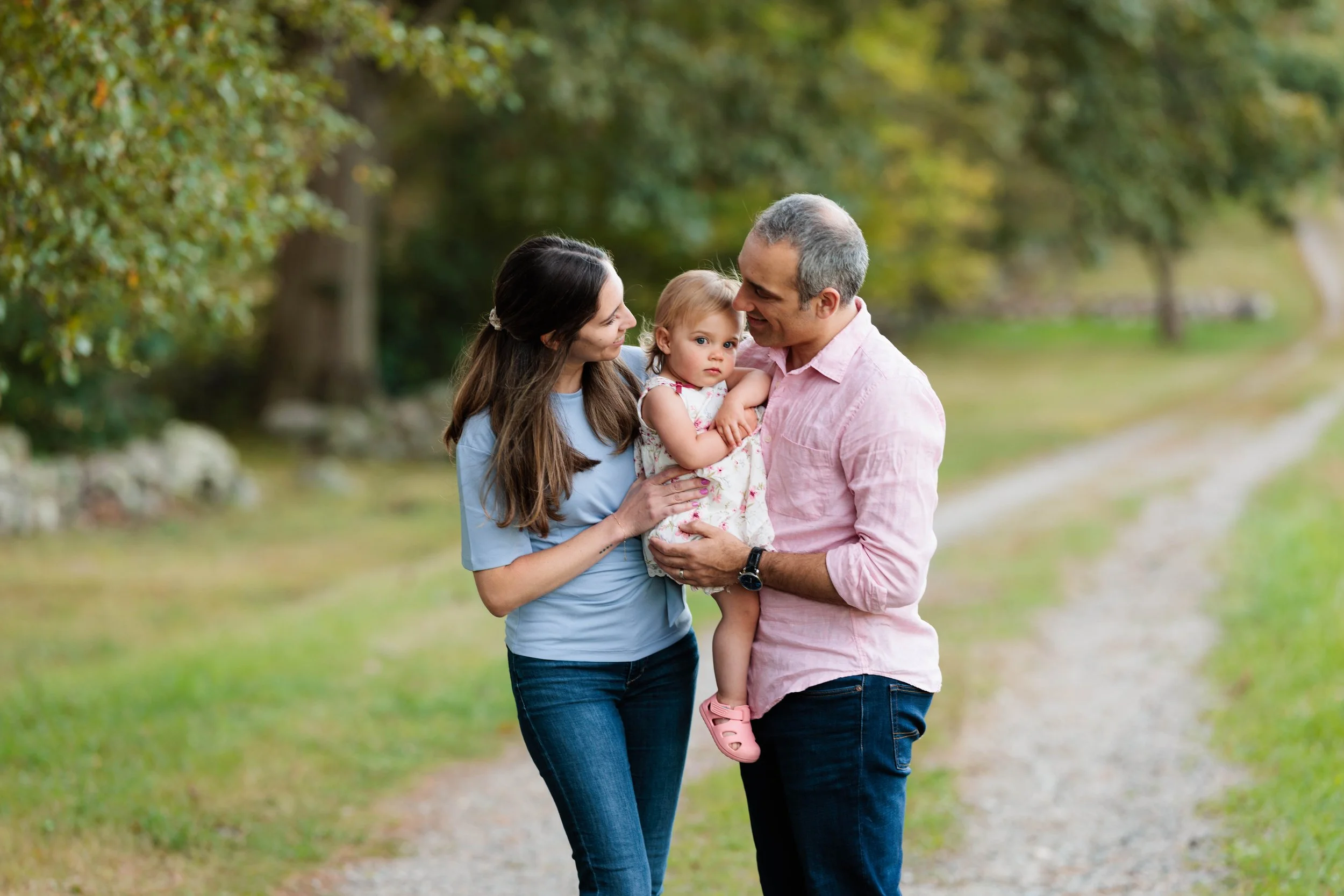 A family of three on a nature trail, with a mother, father, and young daughter, smiling and spending time outdoors.