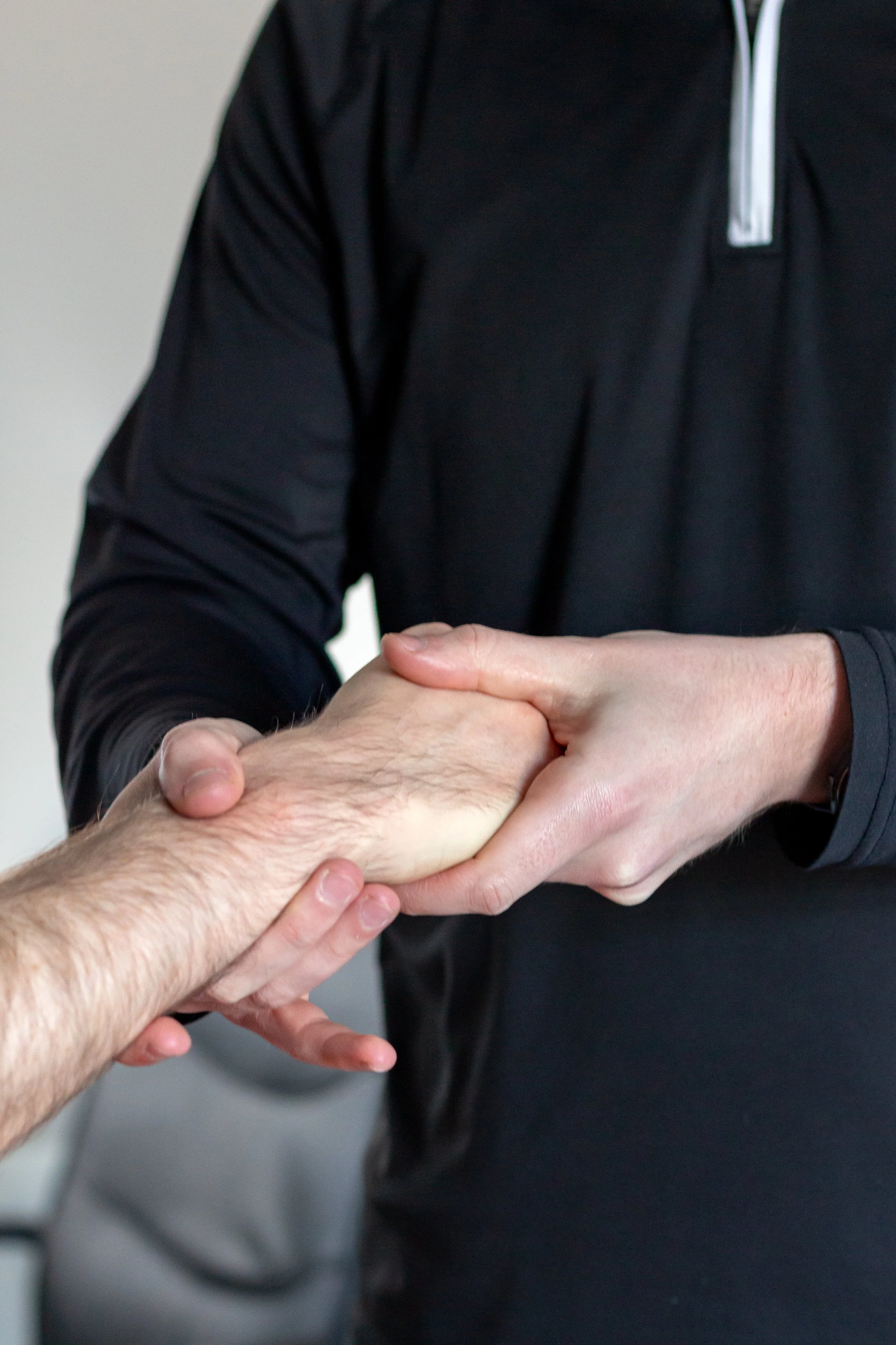 Two people shaking hands, one appears to be giving a handshake to the other.