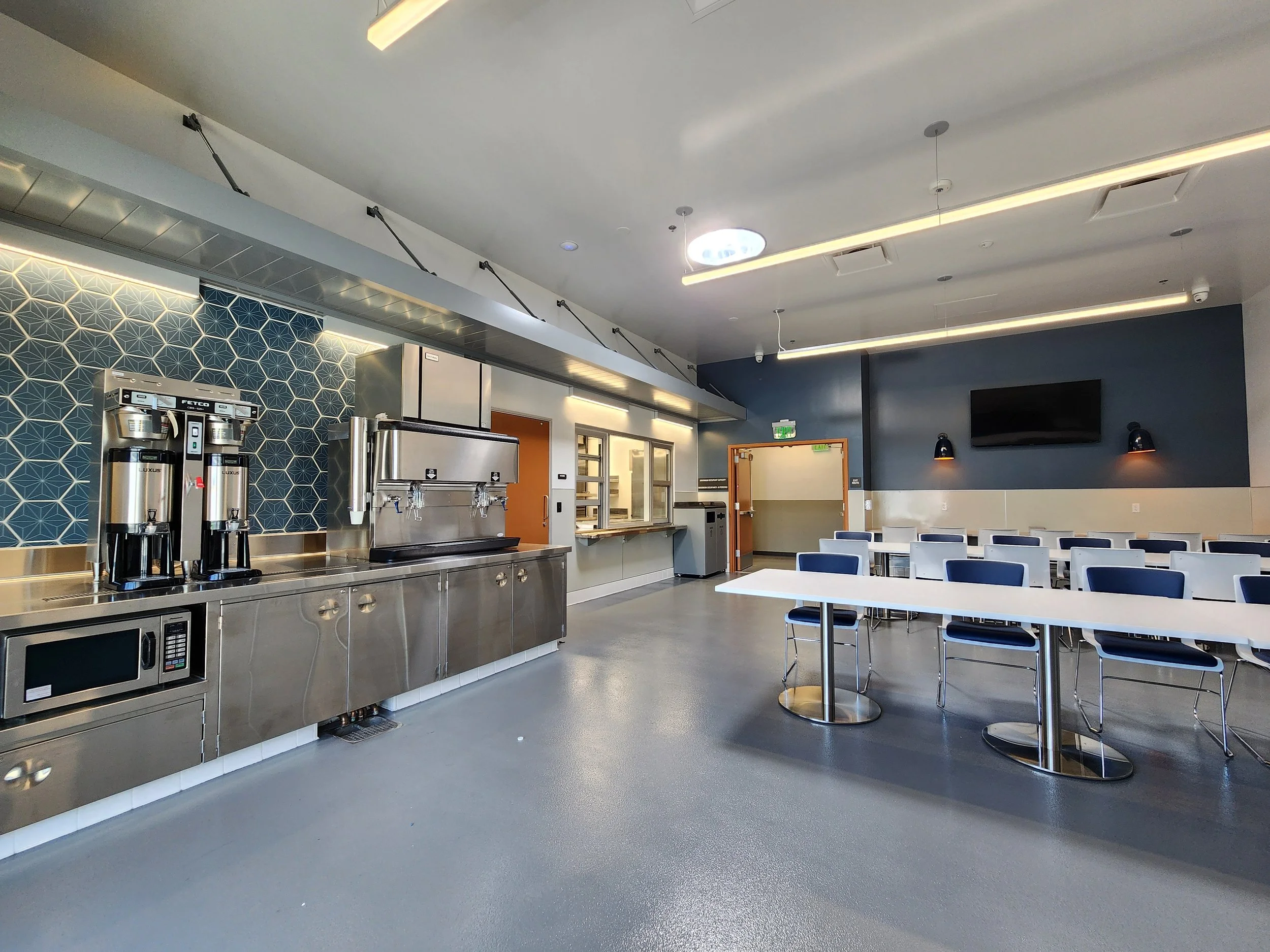 Bright common area with stainless steel counters and bar-height seating inside the Central Cities Navigation Center.