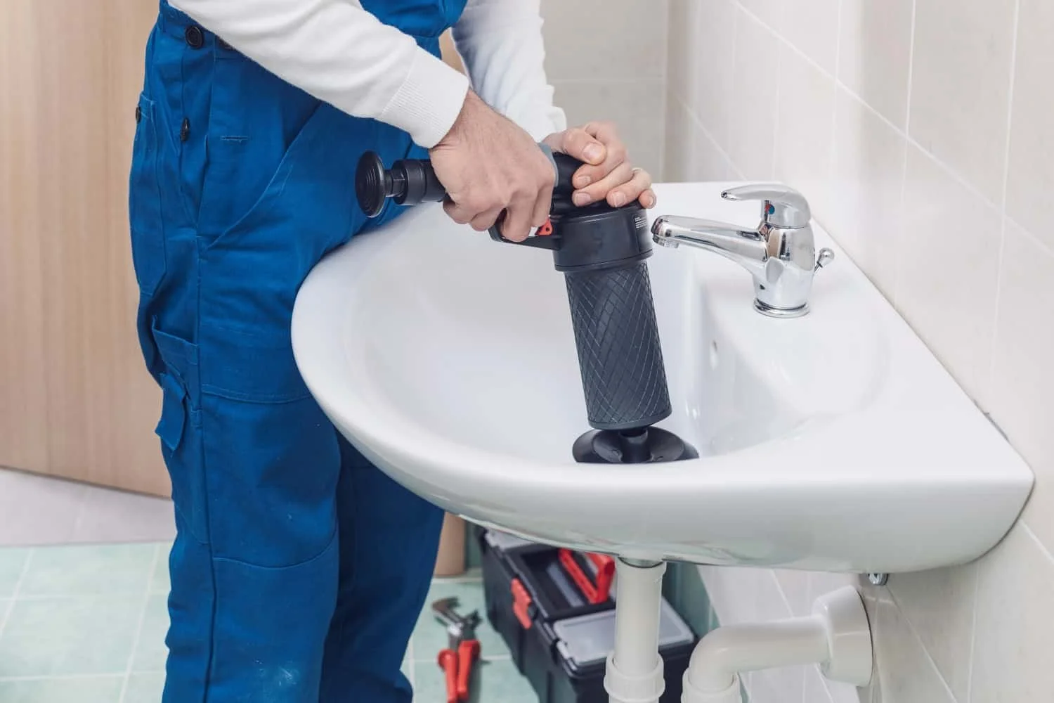 A plumber working on fixing or installing a water filter system in a bathroom sink.