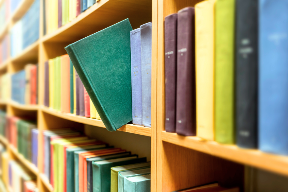 Colorful books arranged on wooden bookshelves in a library.