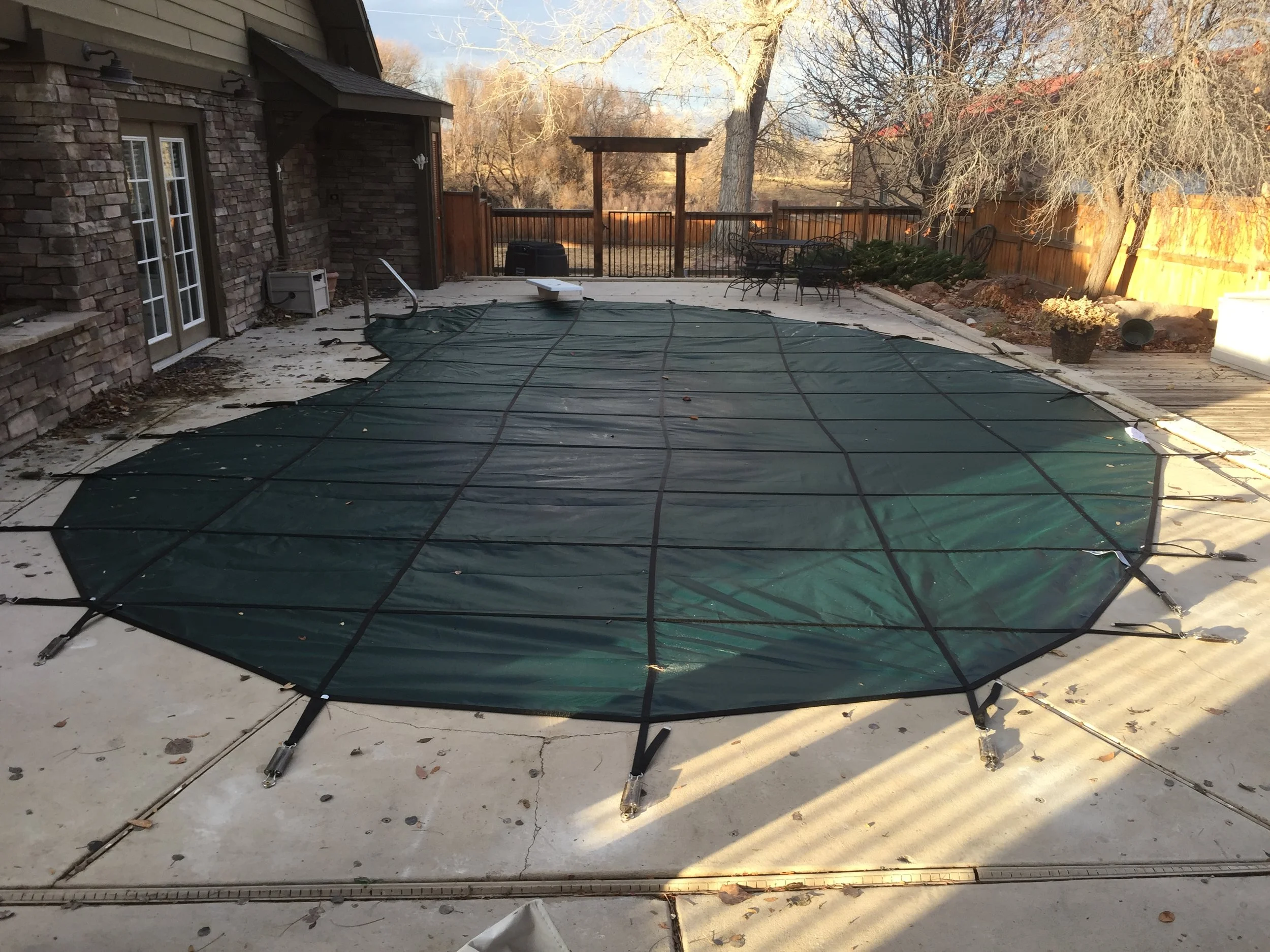 A round above-ground swimming pool cover on a concrete patio.