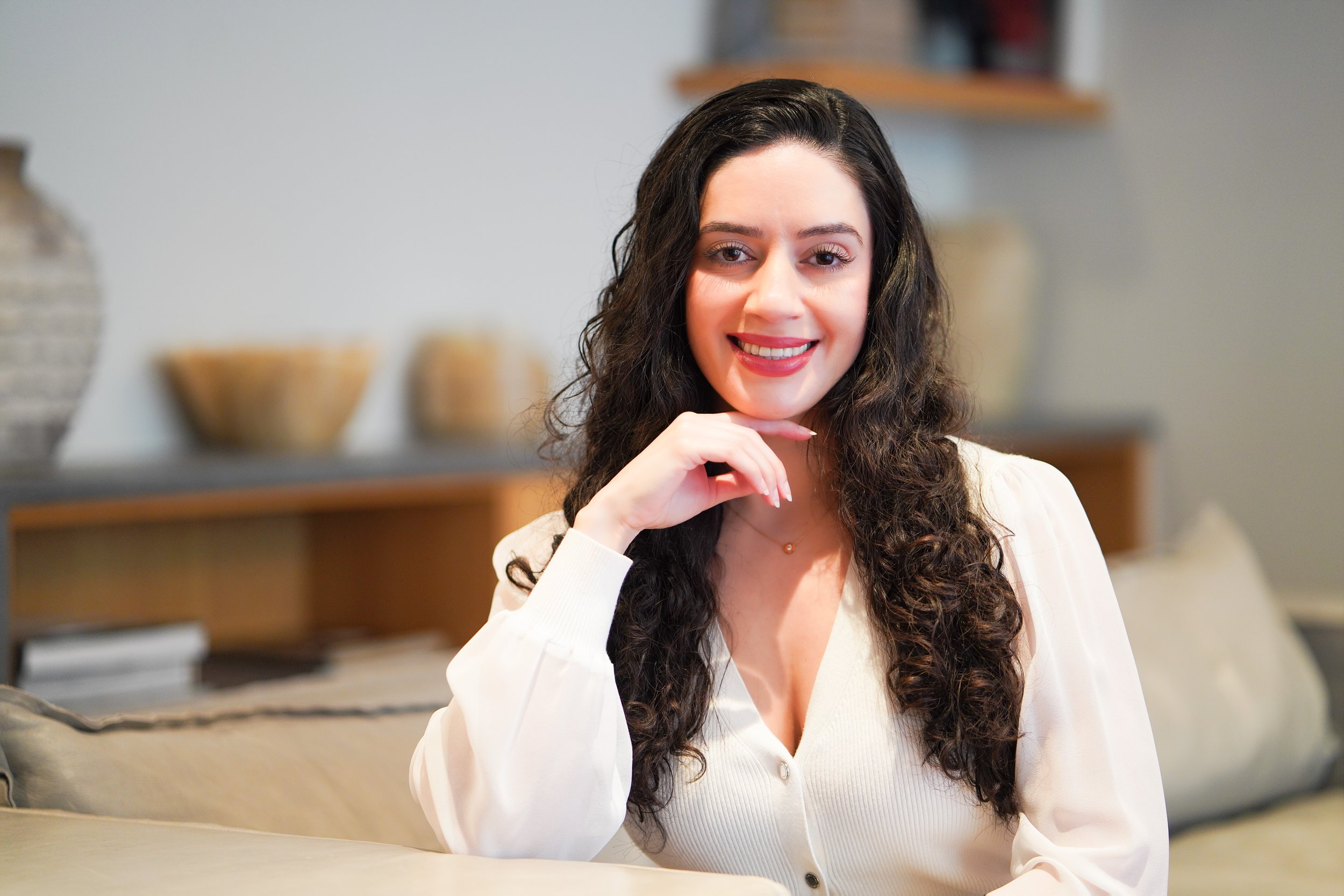 Professional headshot of Setareh Kamali who is smiling at the camera and holding her hand under her chin.