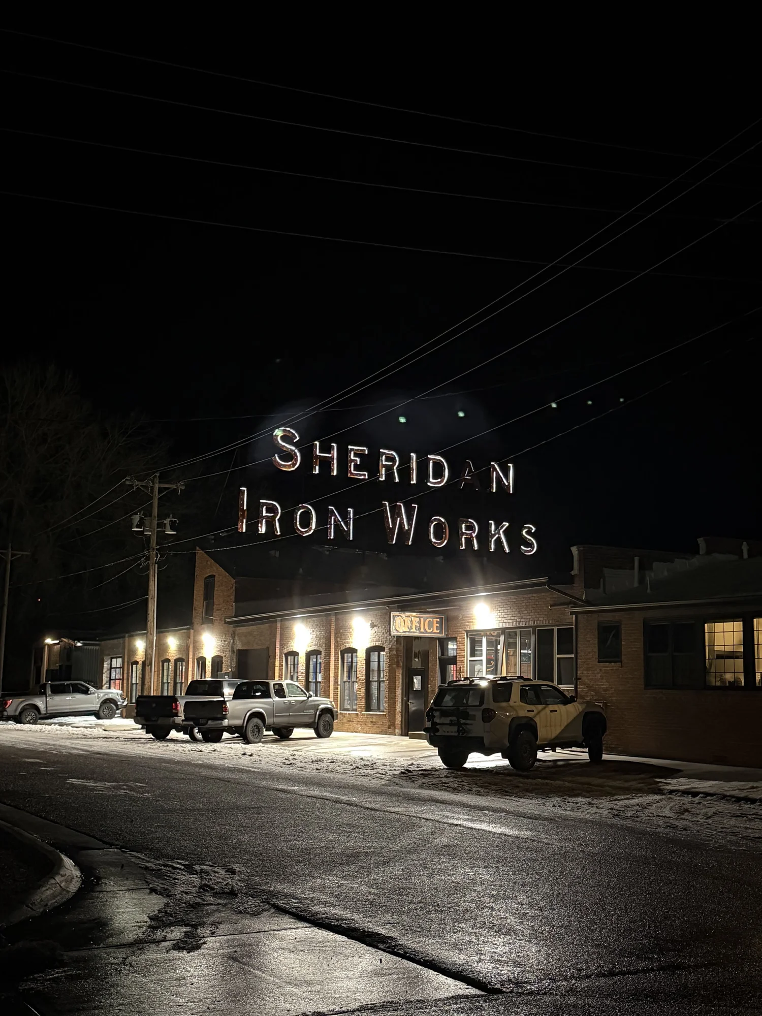 Sheridan Iron Works sign glowing at night in winter