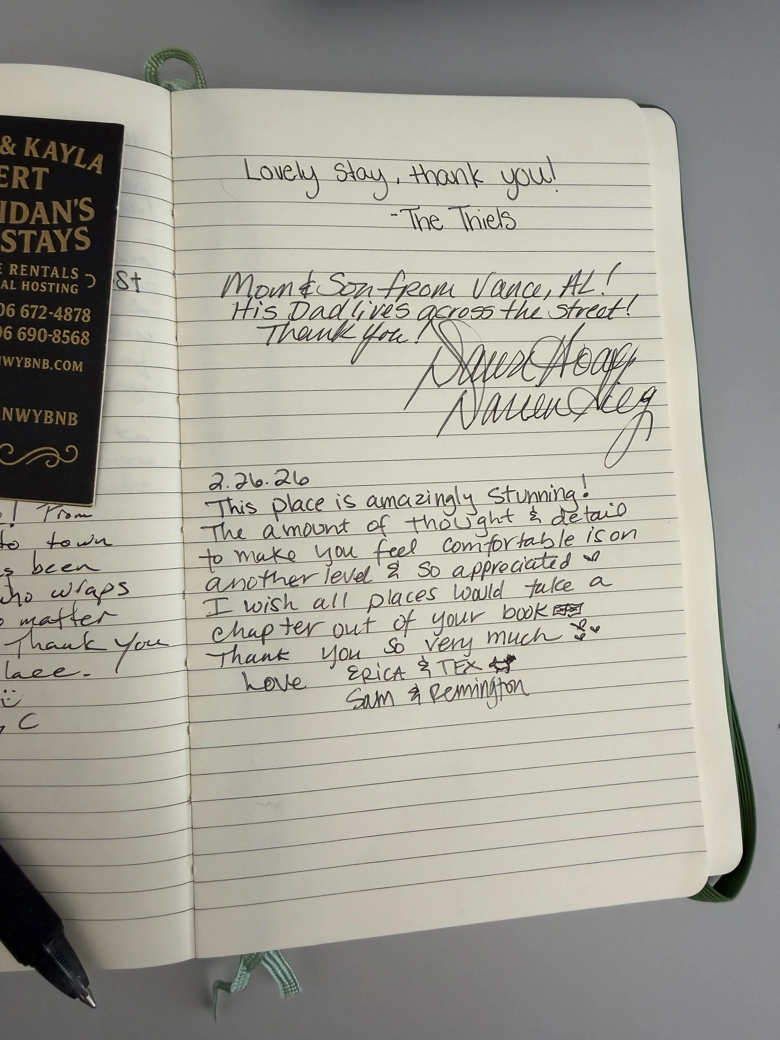Handwritten guest note, pen, and green ribbon bookmark in the Late Checkout WY guestbook.