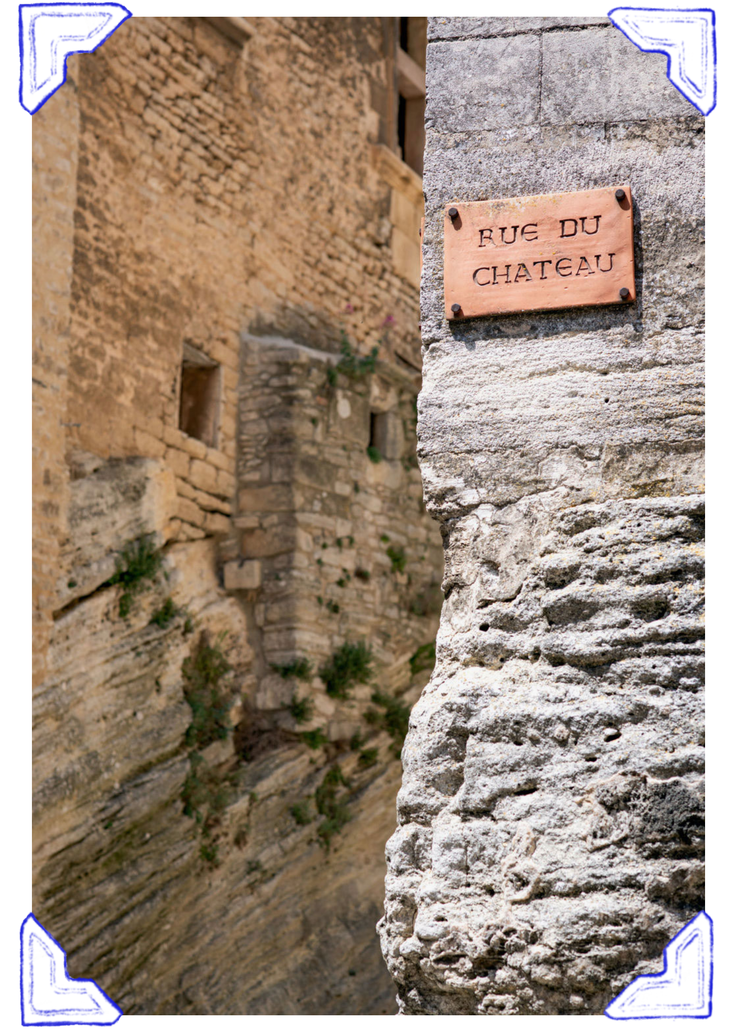 Photo of a street sign on a stone wall that reads 'Rue du Chateau' in a European town.