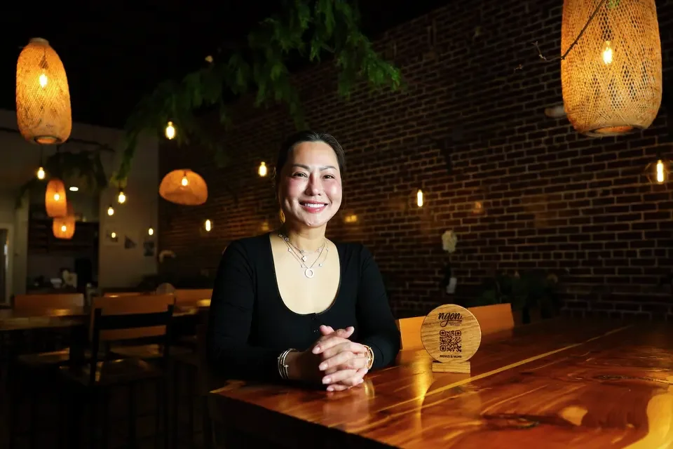 Carol Nguyen smiling at a table in her Dallas-based restaurant, Ngon.