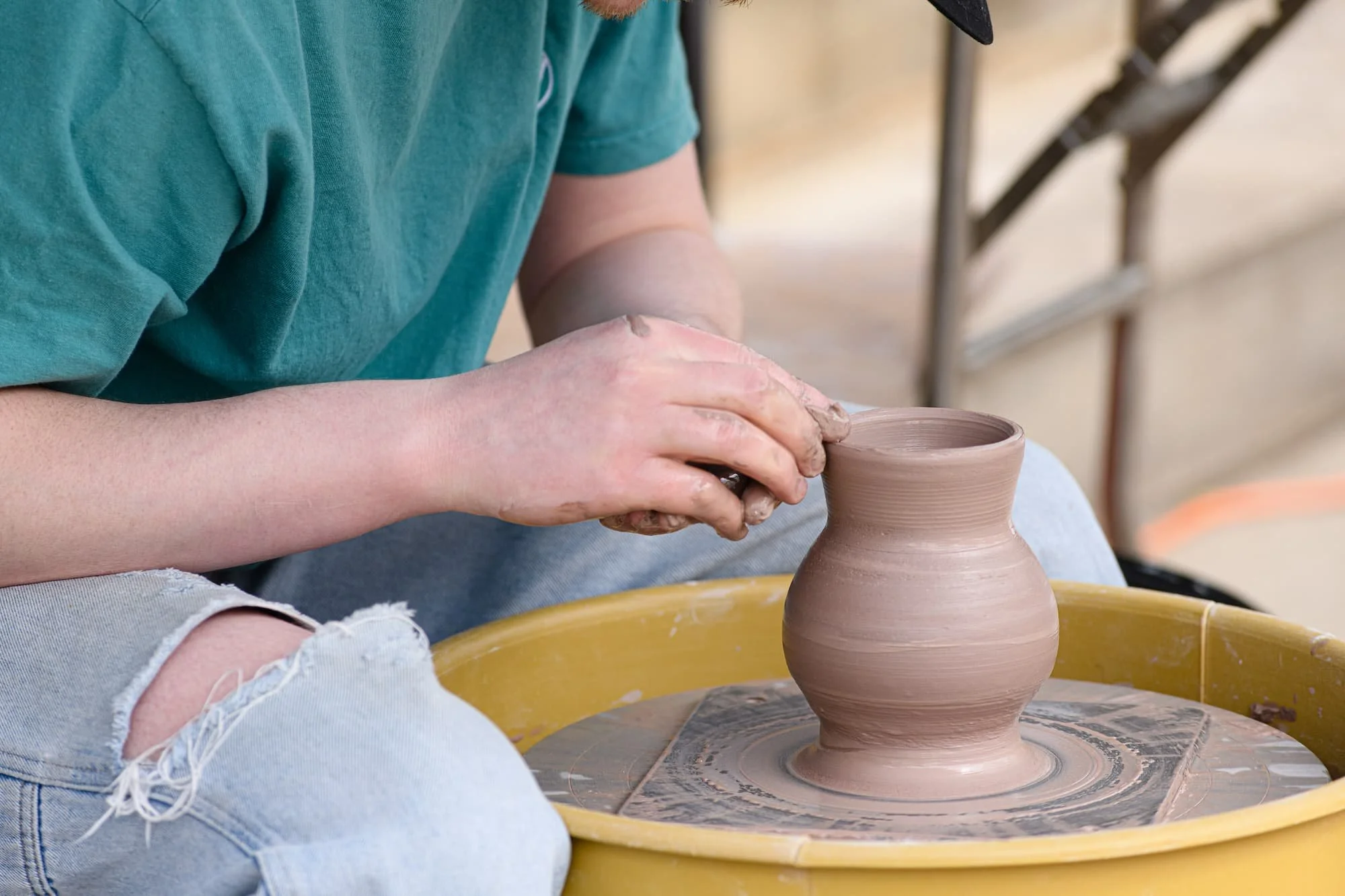 Clay vessel on a yellow wheel during a hands-on demonstration