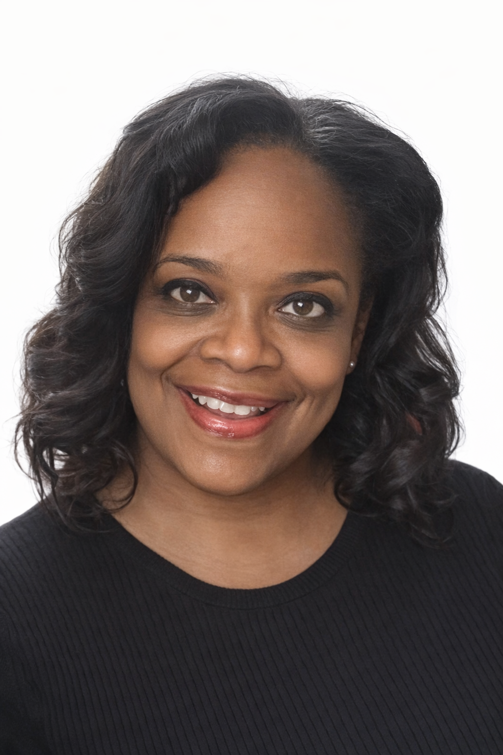 A smiling African American woman with black, wavy hair, wearing a black top, against a white background.