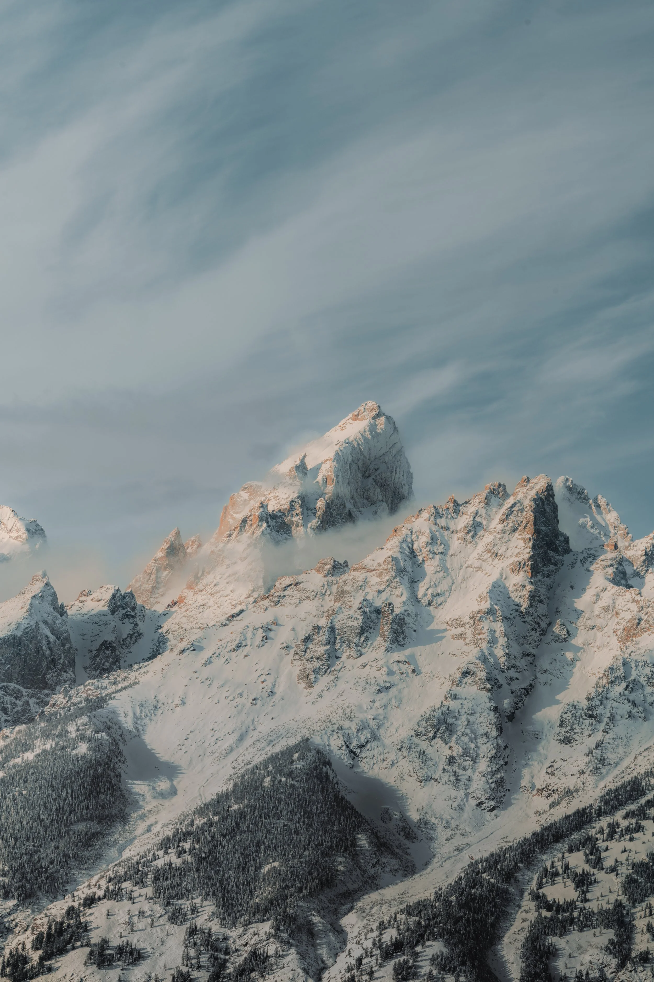 Snow-covered mountain peaks with a partly cloudy sky.