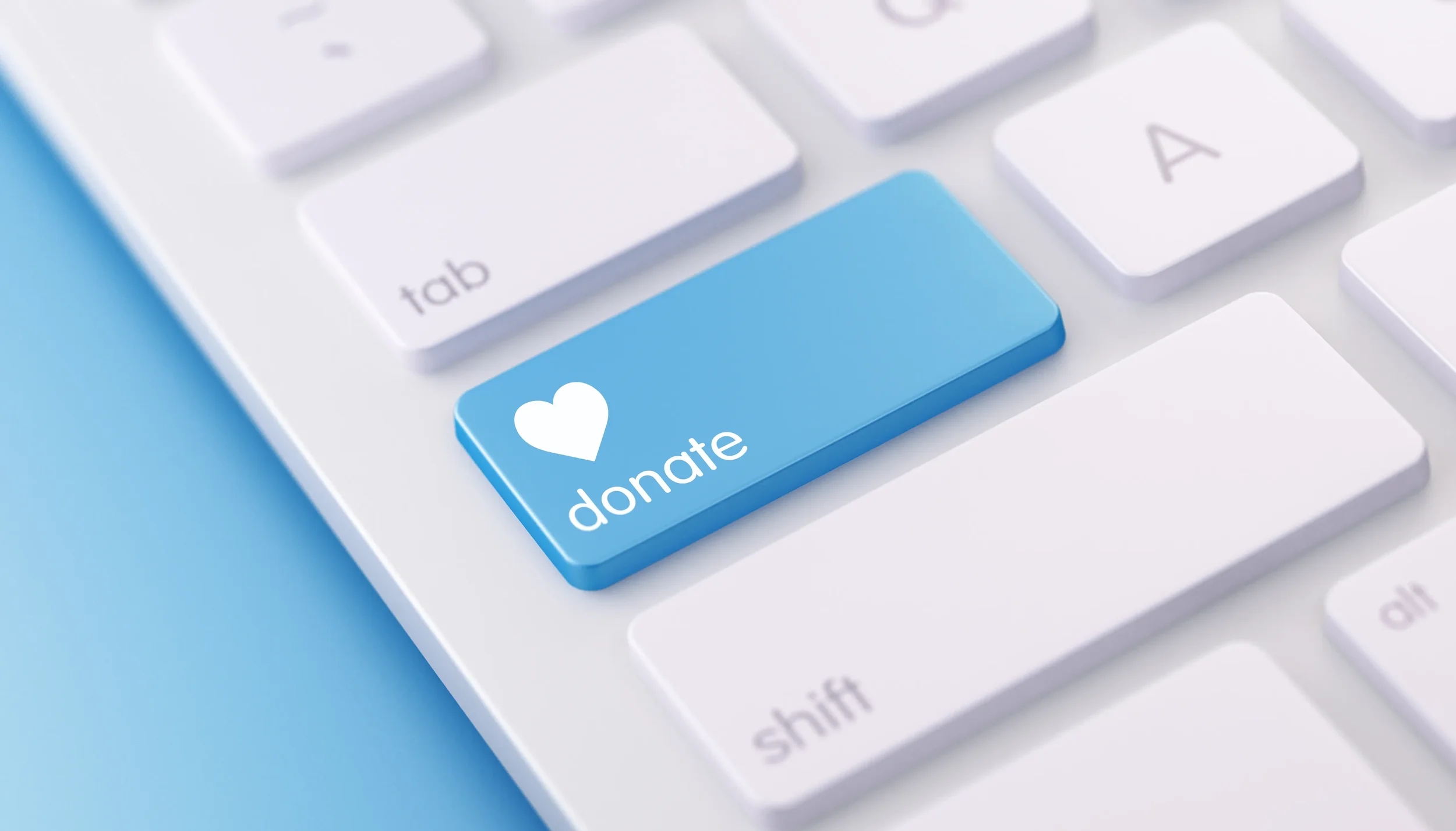 Close-up of a computer keyboard with a blue donation button featuring a white heart icon.