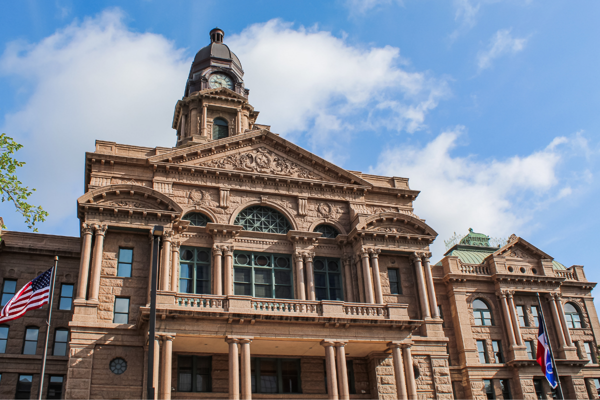 Fort Worth courthouse building with columns, windows, and a clock tower against a blue sky.
