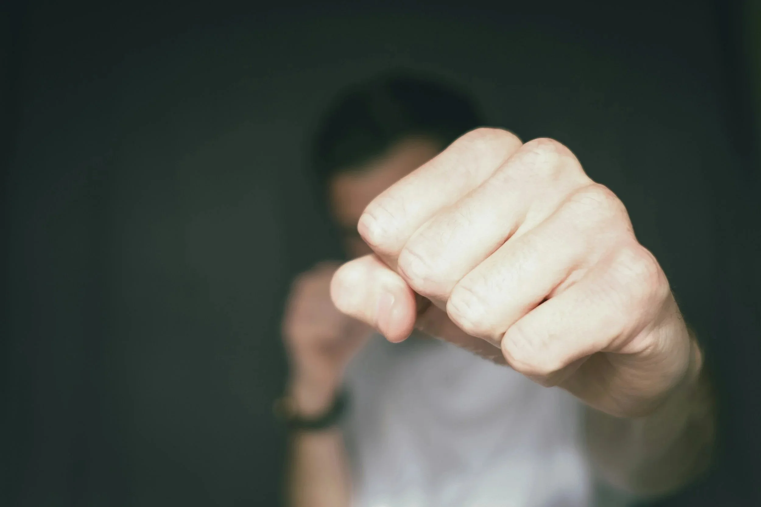 Close-up of a person making a fist, with their face blurred in the background.