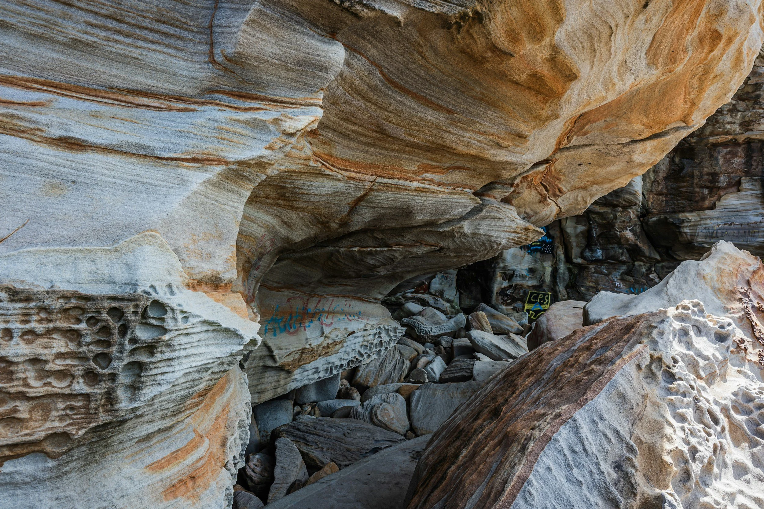Close-up view of layered colorful rocks with patterns and textures, some graffiti visible on rocks.
