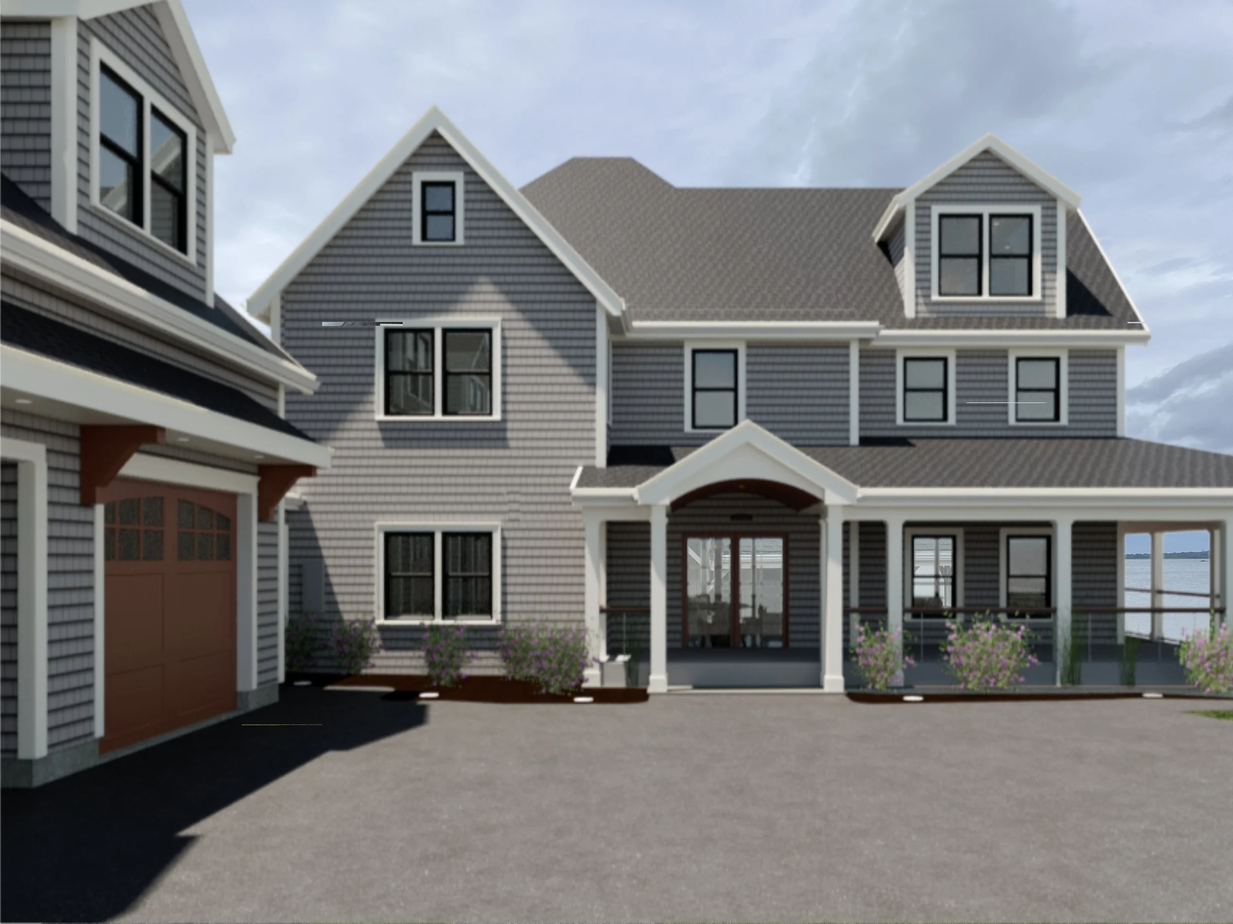 A large gray house with a porch, multiple windows, and a garage with a brown door, near a body of water and a cloudy sky in the background.