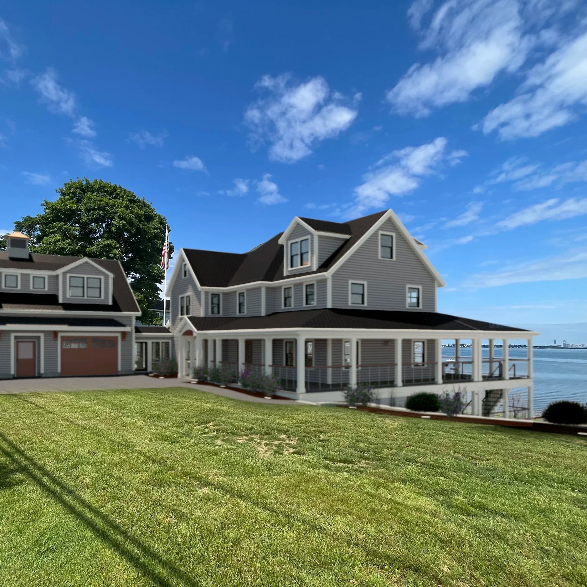 A large gray house with multiple gabled roofs and a wraparound porch, overlooking a body of water on a sunny day with blue sky and scattered clouds.