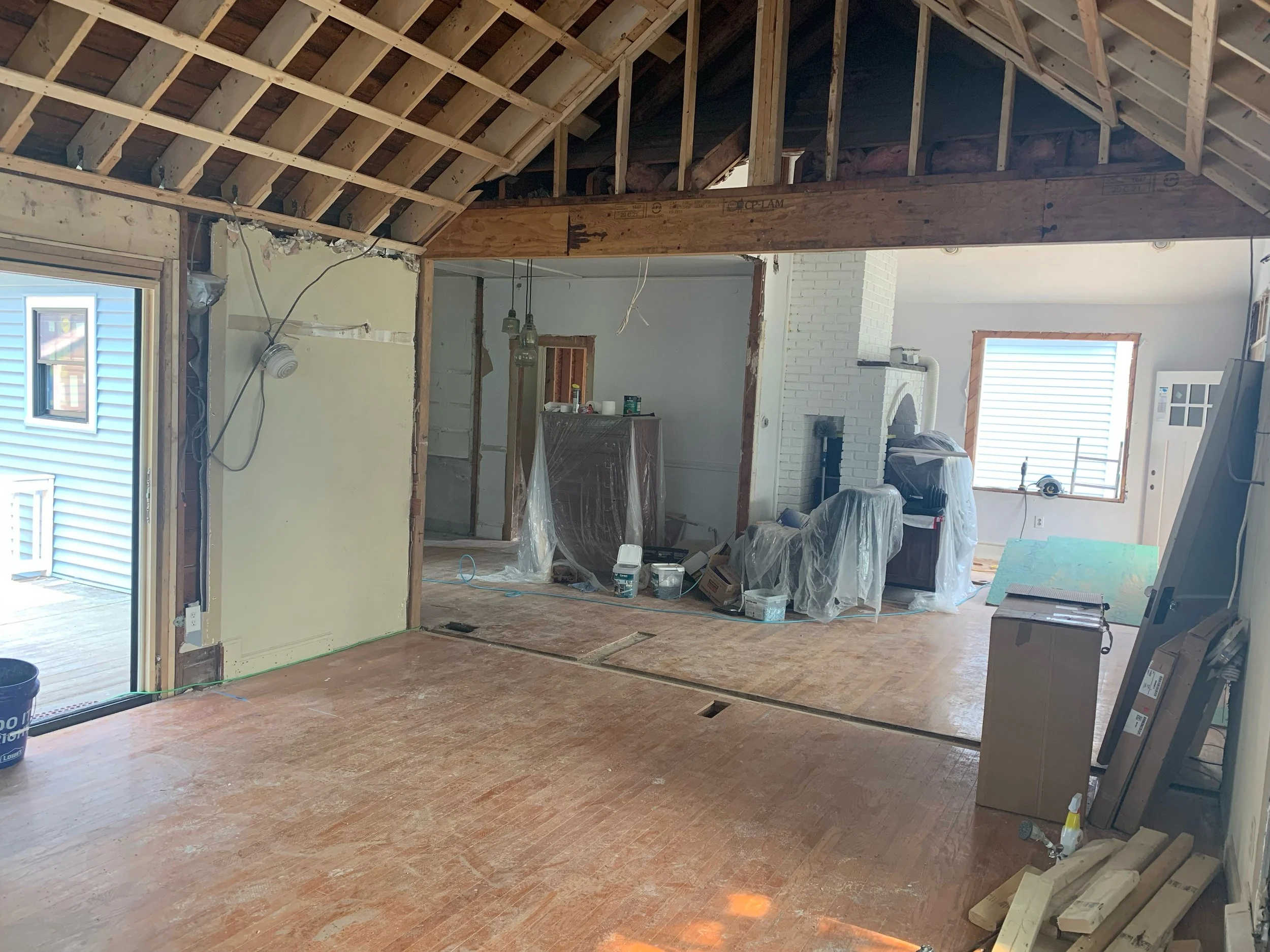 Interior of a house under construction or renovation, showing exposed wooden framing, construction materials, and partially finished walls and ceilings.