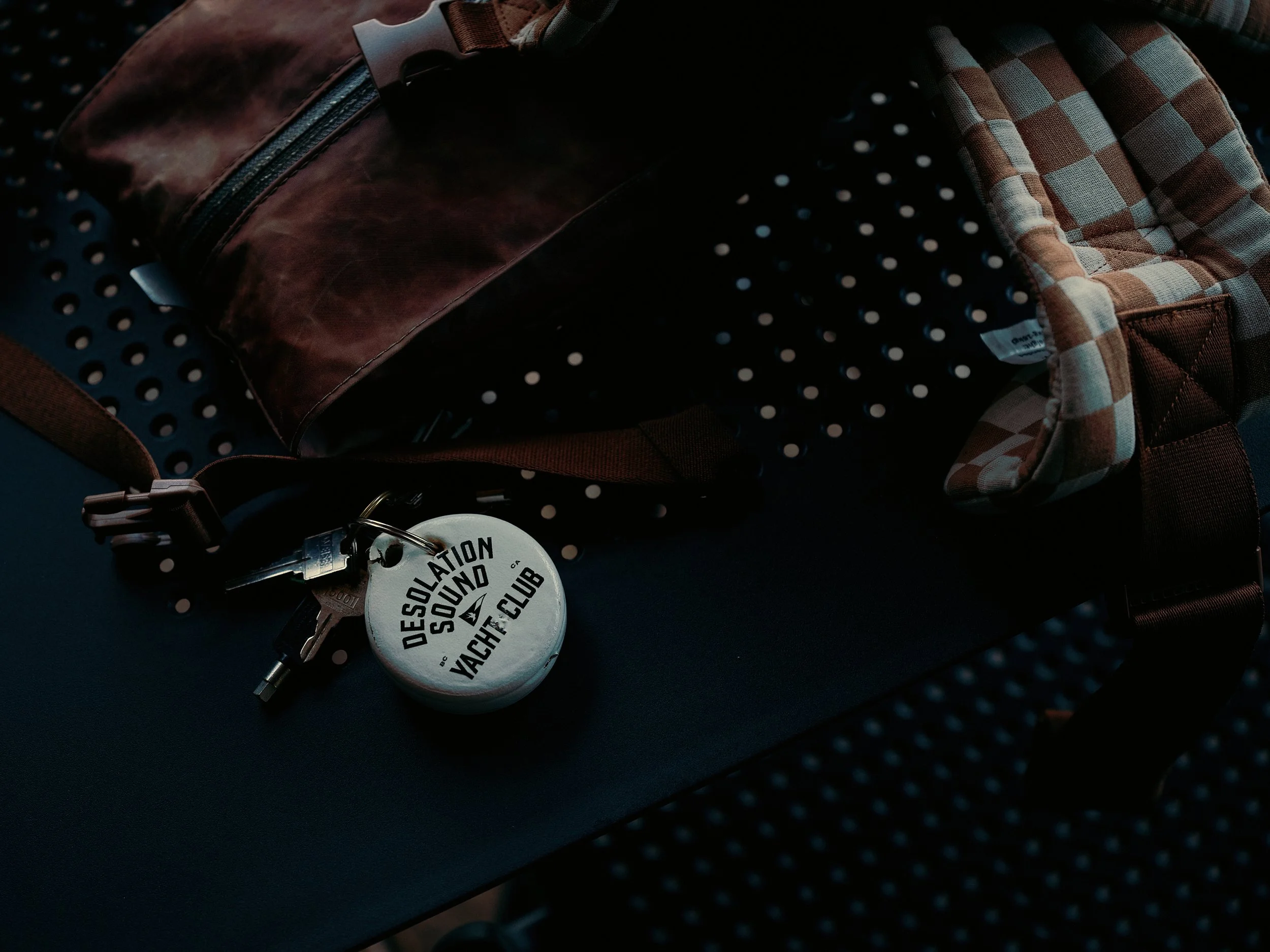 Close-up of a set of keys with a round keychain that reads 'Desolation Sound Yacht Club' resting on a dark table
