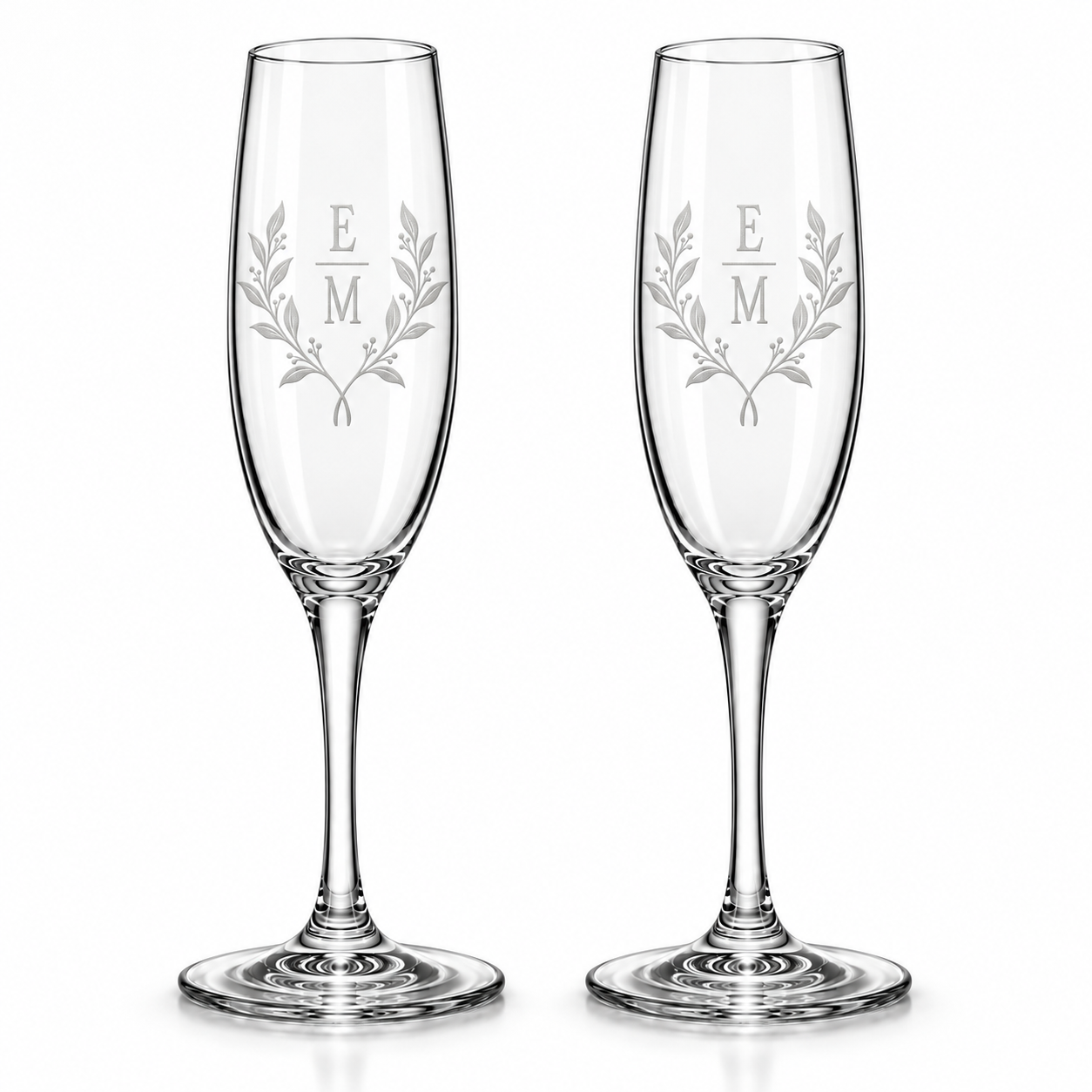 Set of two personalized wedding champagne flutes with stacked initials, botanical wreath design, and wedding date, permanently sand-carved into clear glass.