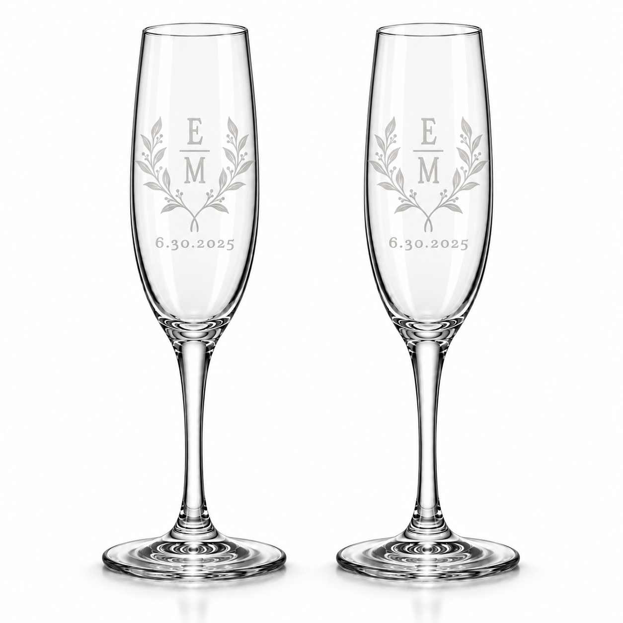 Matching pair of custom engraved champagne flutes featuring stacked couple's initials, delicate botanical branches, and a personalized wedding date.