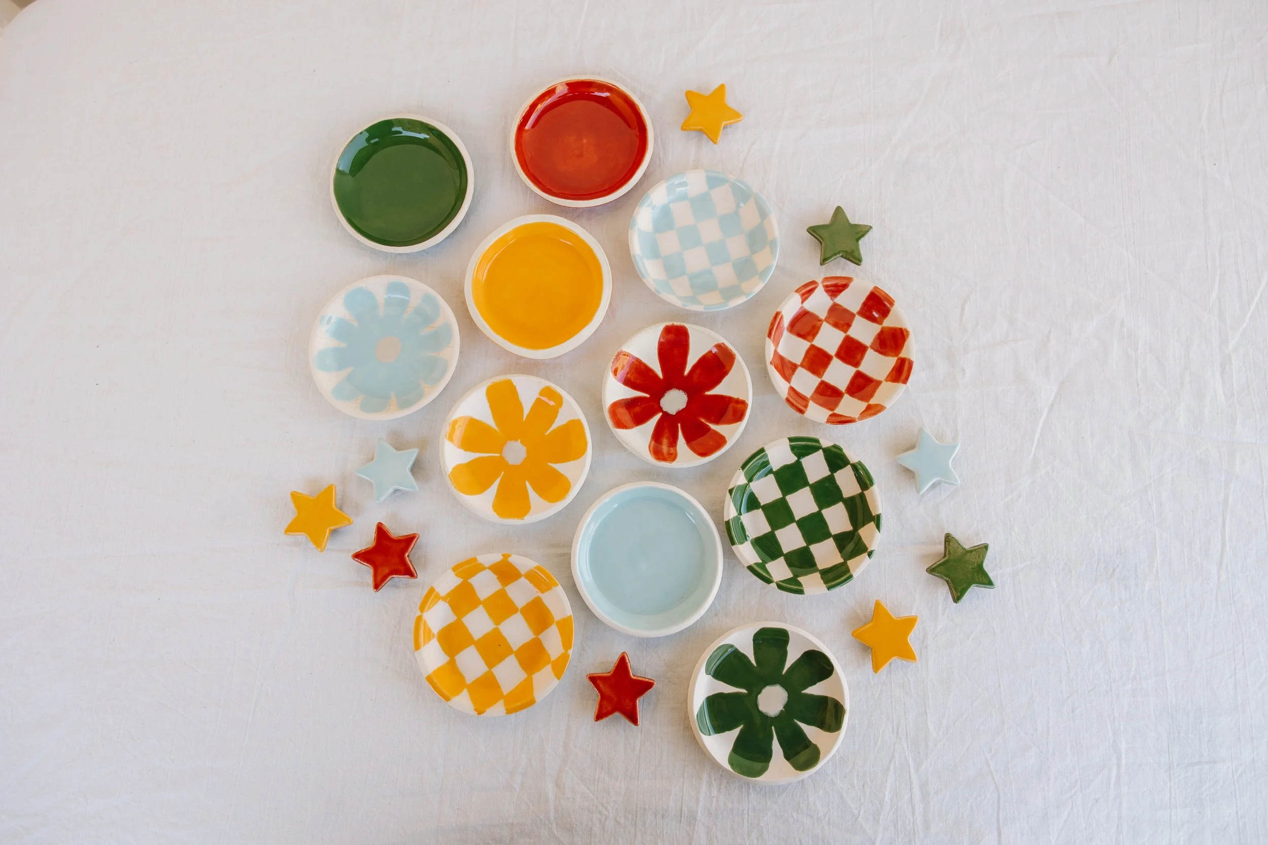 Colorful small bowls with various patterns and star-shaped decorations on a white surface.