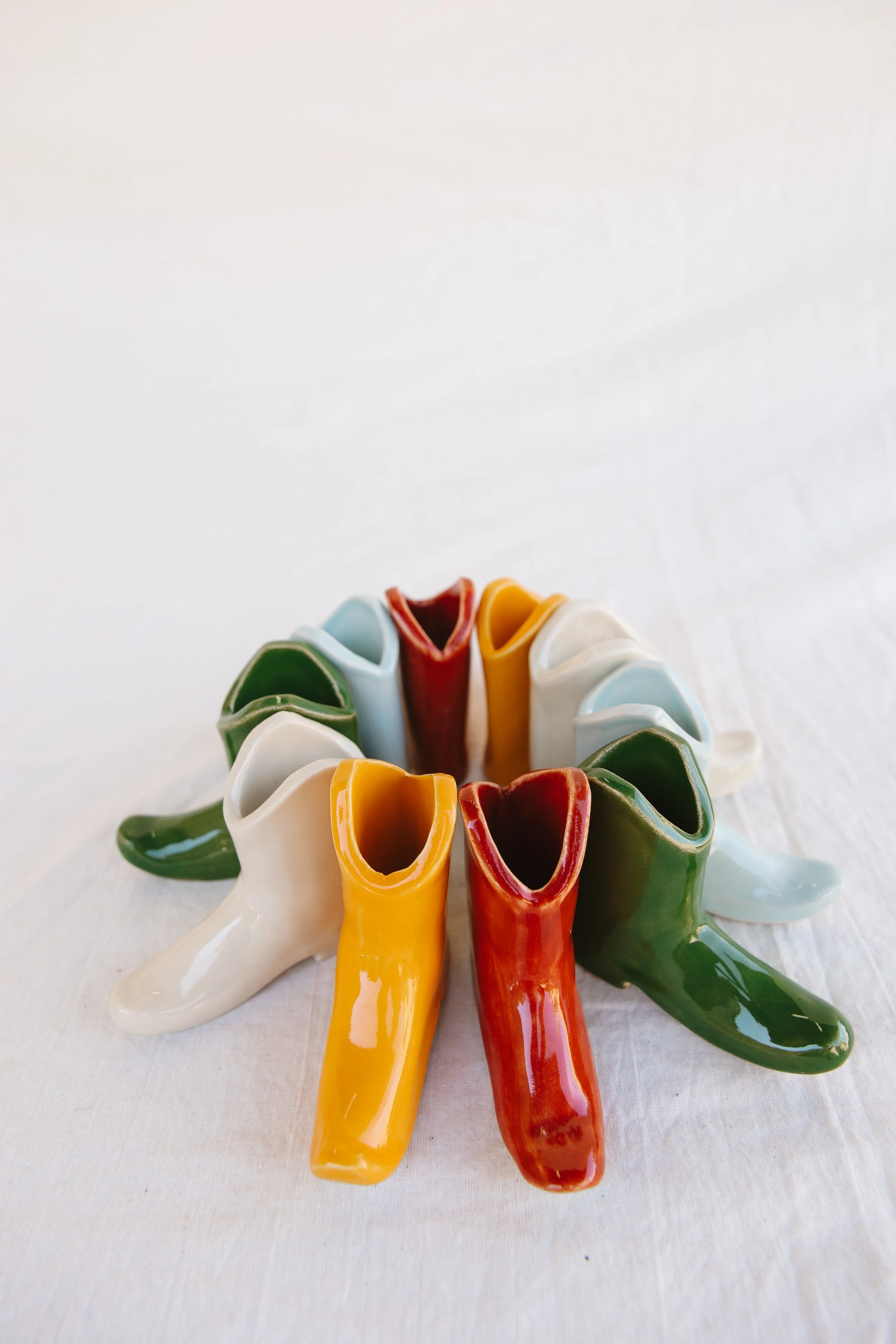 Colorful ceramic flower vases arranged in a circle on a white surface.