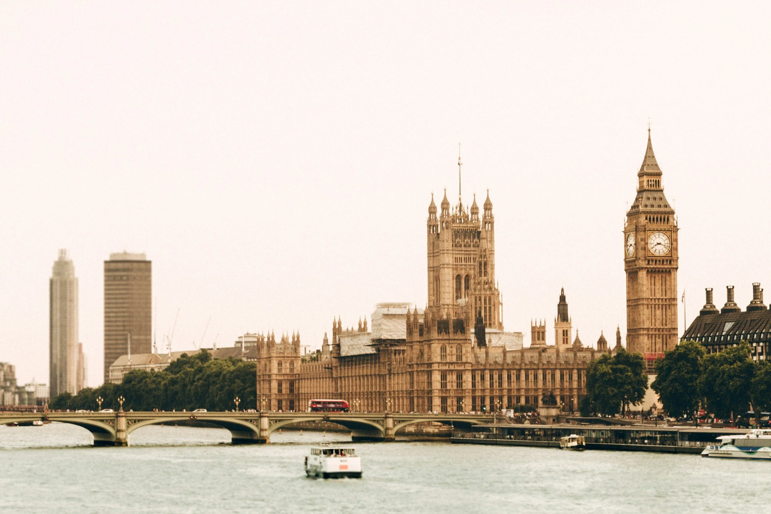 A view of London's skyline over the River Thames, featuring the Houses of Parliament with Big Ben and several high-rise buildings in the background.