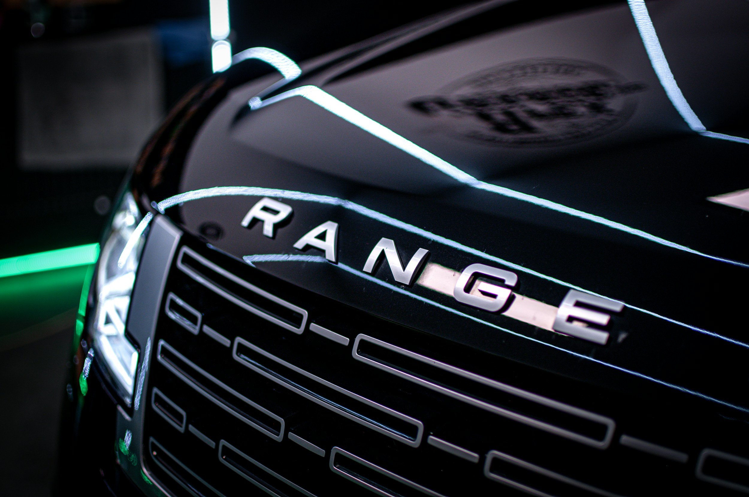 Close-up of a black Range Rover vehicle with illuminated lights and the brand name on the grille.